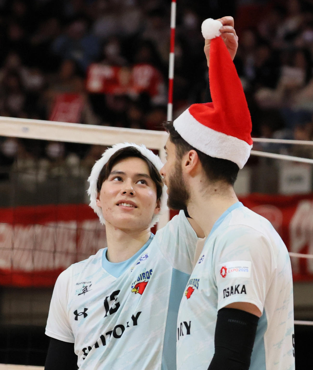 サントリー対名古屋　試合後のセレモニーでシリフカ（右）のサンタ帽子をつかむサントリー高橋藍（撮影・清水貴仁）