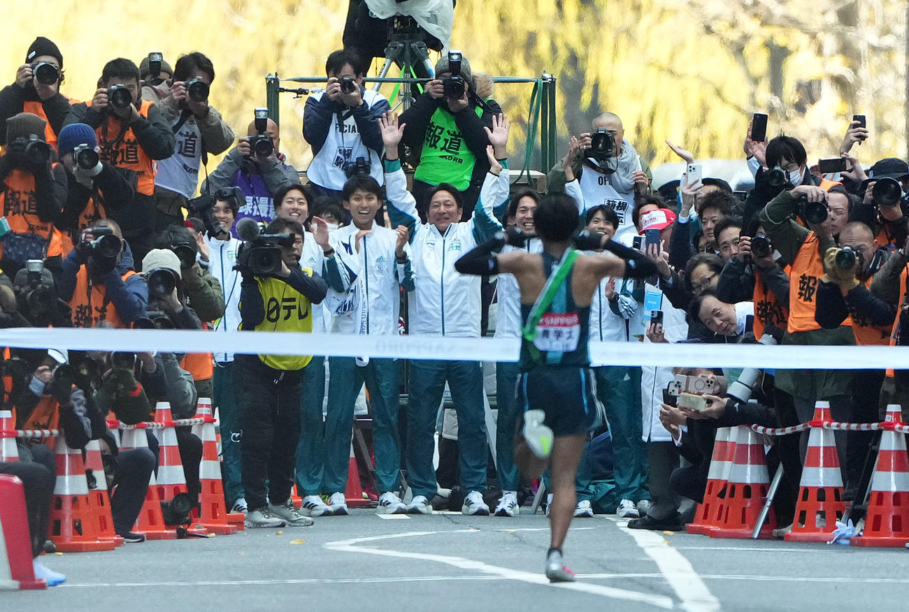 1位でゴールテープをきる青学大10区小河原陽琉を迎える原監督（中央）ら選手たち（撮影・菅敏）