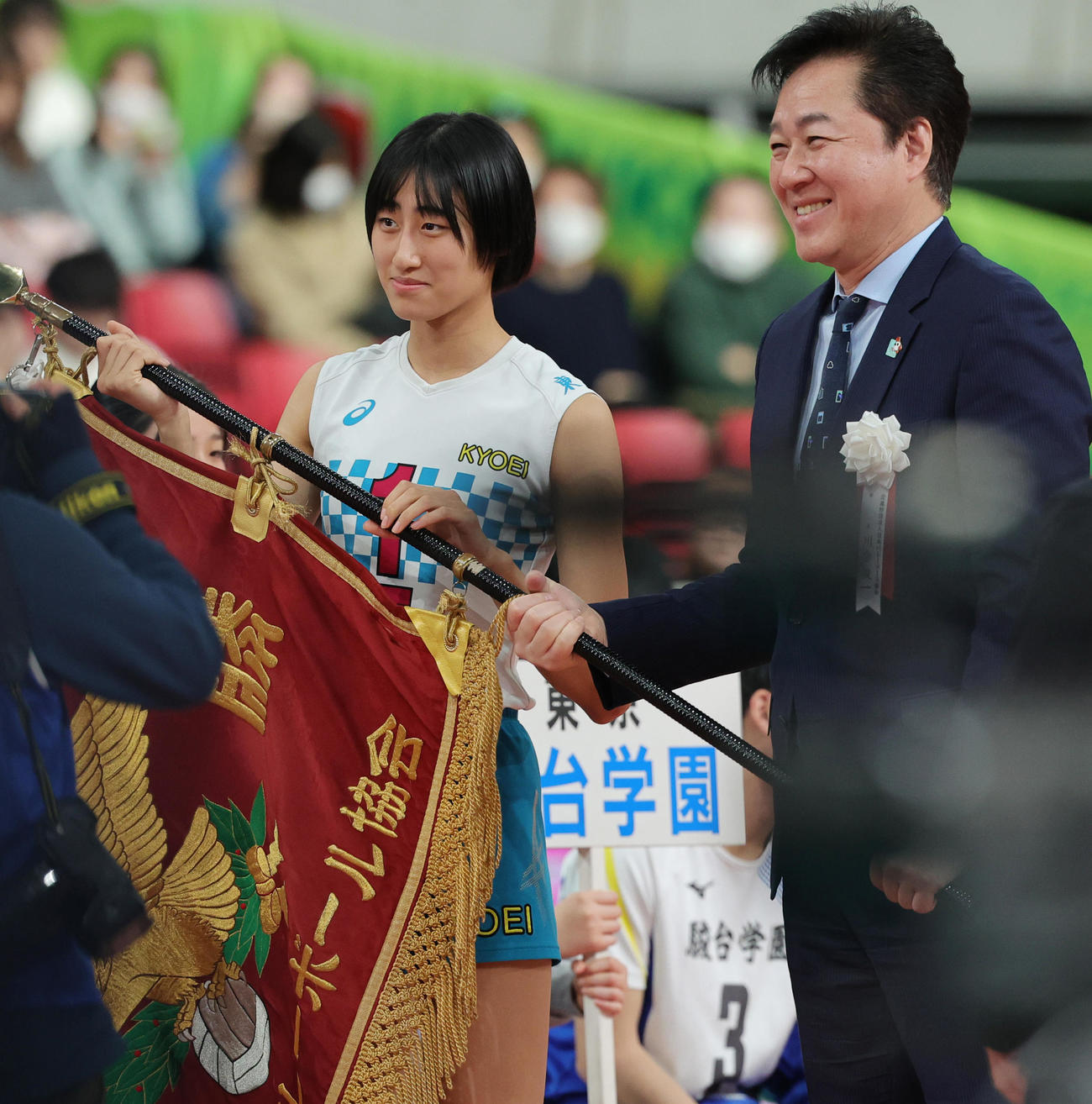共栄学園対下北沢成徳　日本バレーボール協会・川合会長（右）から優勝旗を受けとる共栄学園・秋本（撮影・野上伸悟）