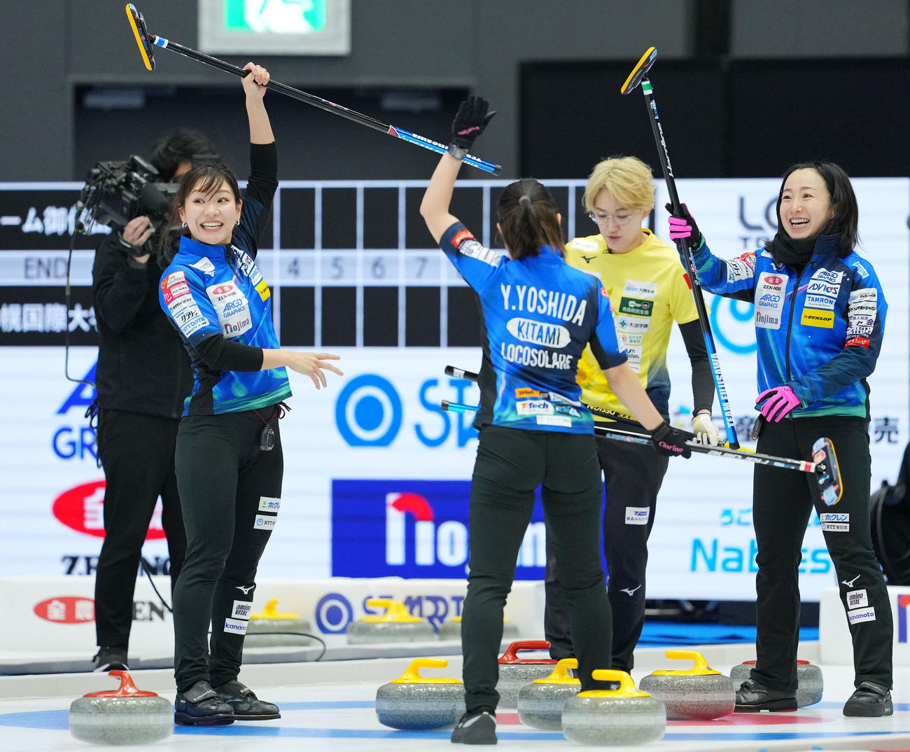 ロコ・ソラーレ対フィロシーク青森　第1エンド、スティックを掲げるロコ・ソラーレ吉田知（左）と藤沢（右）（撮影・横山健太）