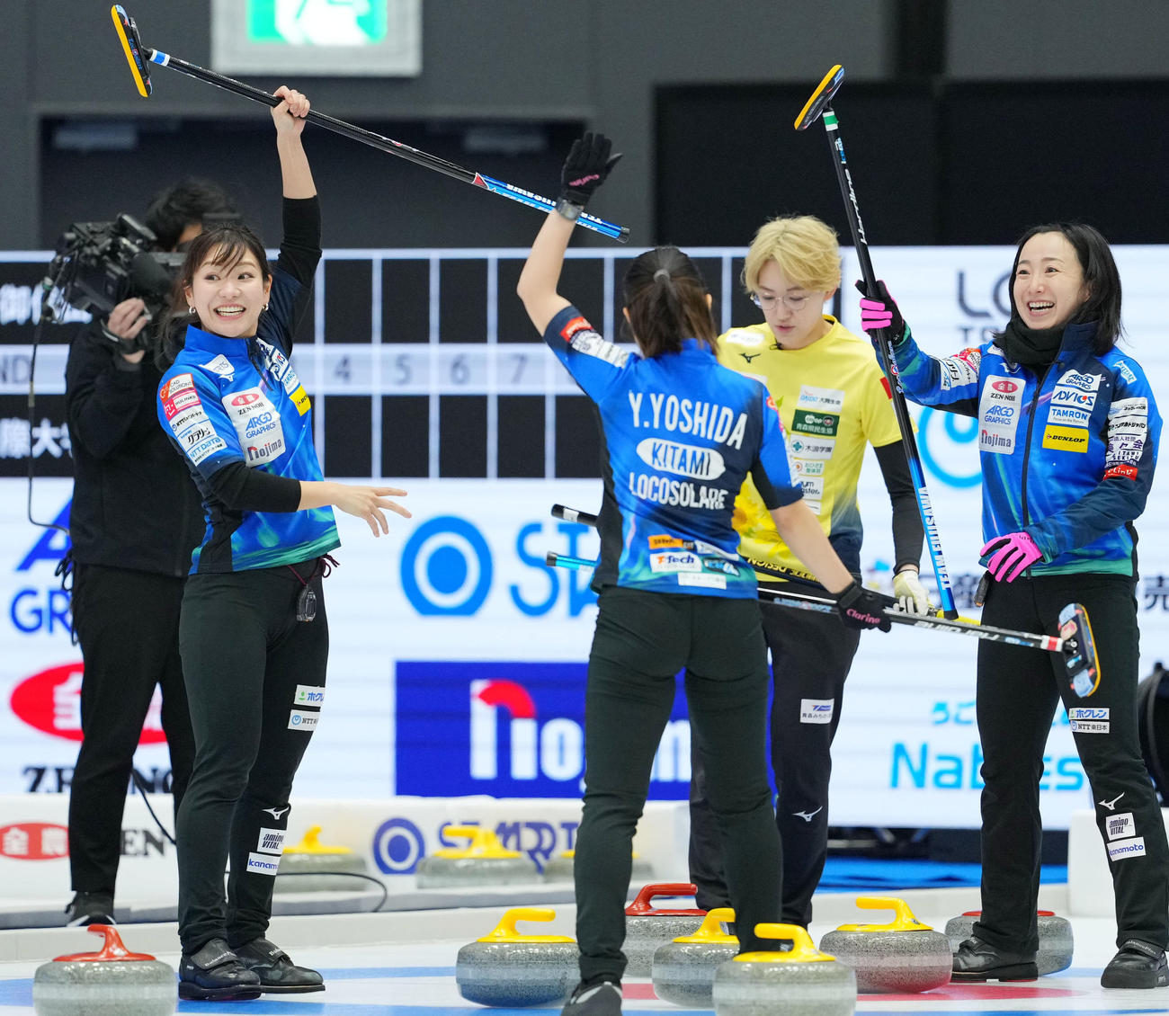 ロコ・ソラーレ対フィロシーク青森　第1エンド、スティックを掲げるロコ・ソラーレ吉田知（左）と藤沢（右）（撮影・横山健太）