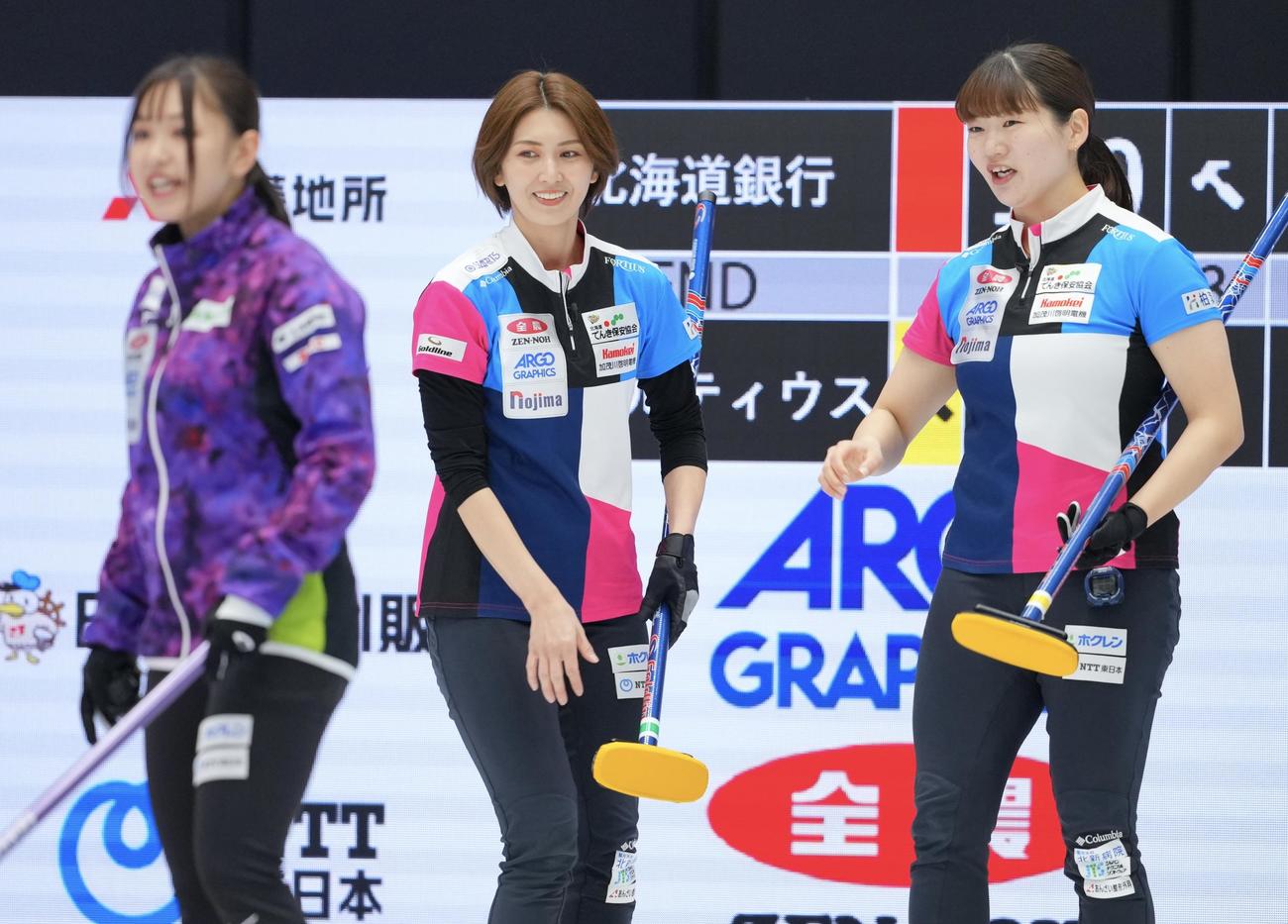 フォルティウス対北海道銀行　第3エンド、ストーンを投じ笑顔を見せるフォルティウス吉村（中央）と小谷（右）（撮影・垰建太）