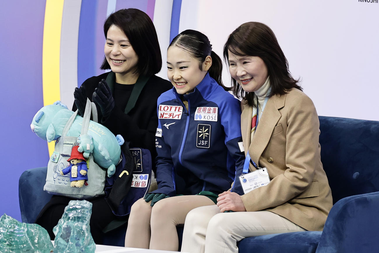 女子SPの得点を確認し、笑顔の島田麻央（中央）。右は浜田美栄コーチ（共同）