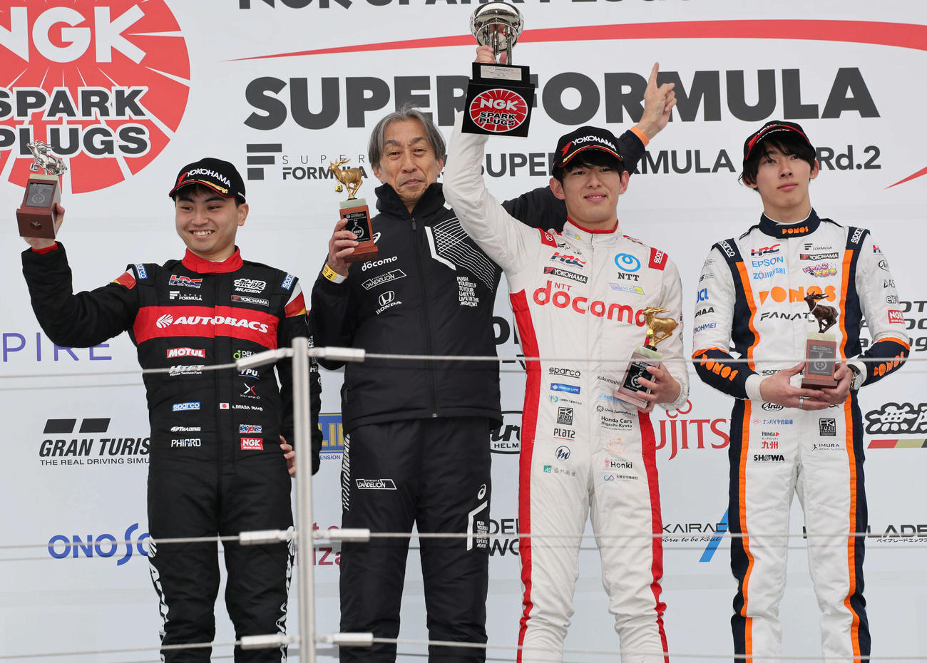 スーパーフォーミュラ開幕戦の表彰台で笑顔を見せる、左から2位の岩佐歩夢、優勝したDOCOMO TEAM DANDELION RACINGの村岡潔監督と太田格之進、3位の佐藤蓮（撮影・宮崎幸一）