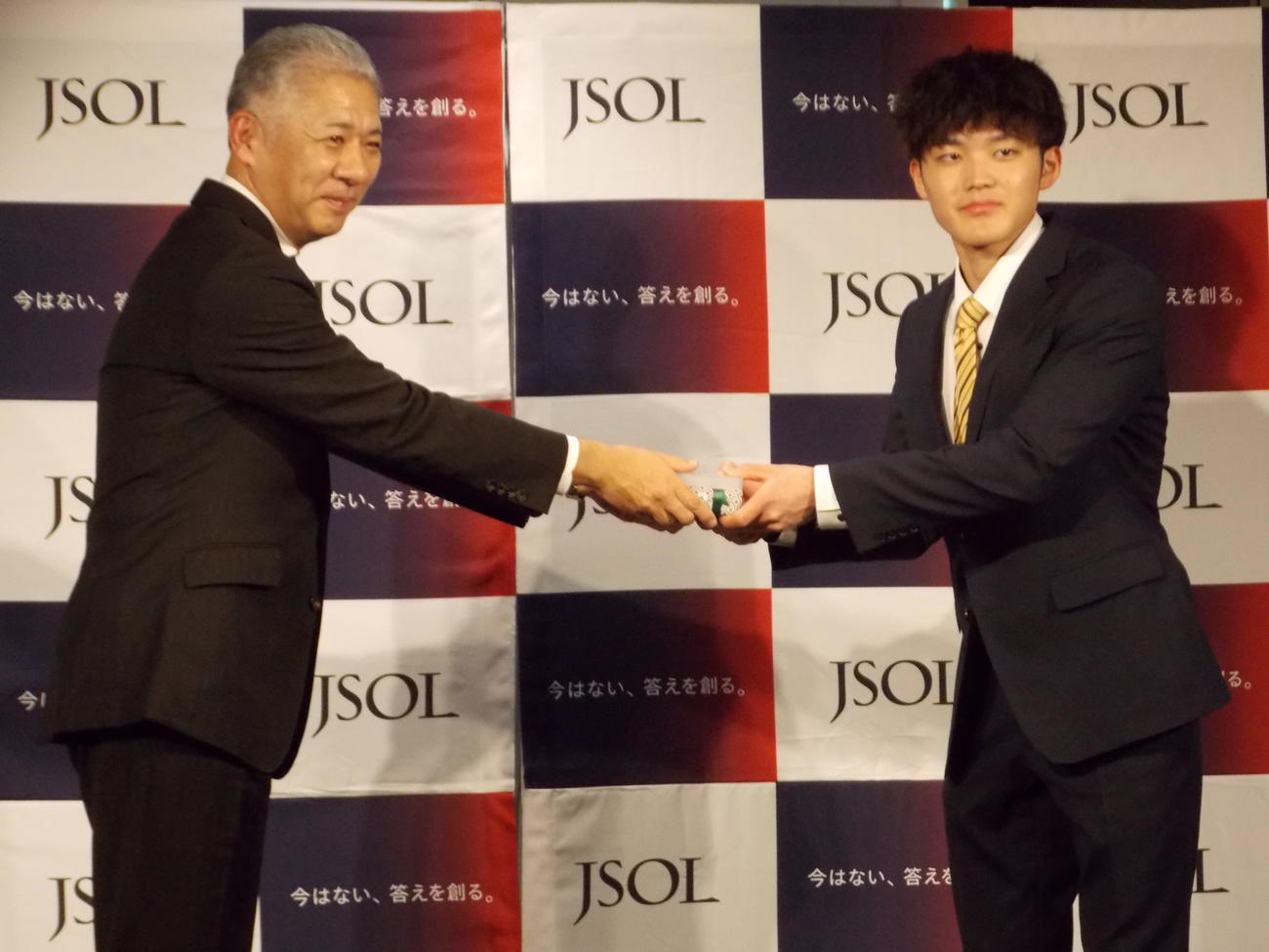 千葉・八千代高を卒業した安楽宙斗（右）は、所属するJSOLの永井健志社長から名刺と名刺入れを受け取る（撮影・松本航）