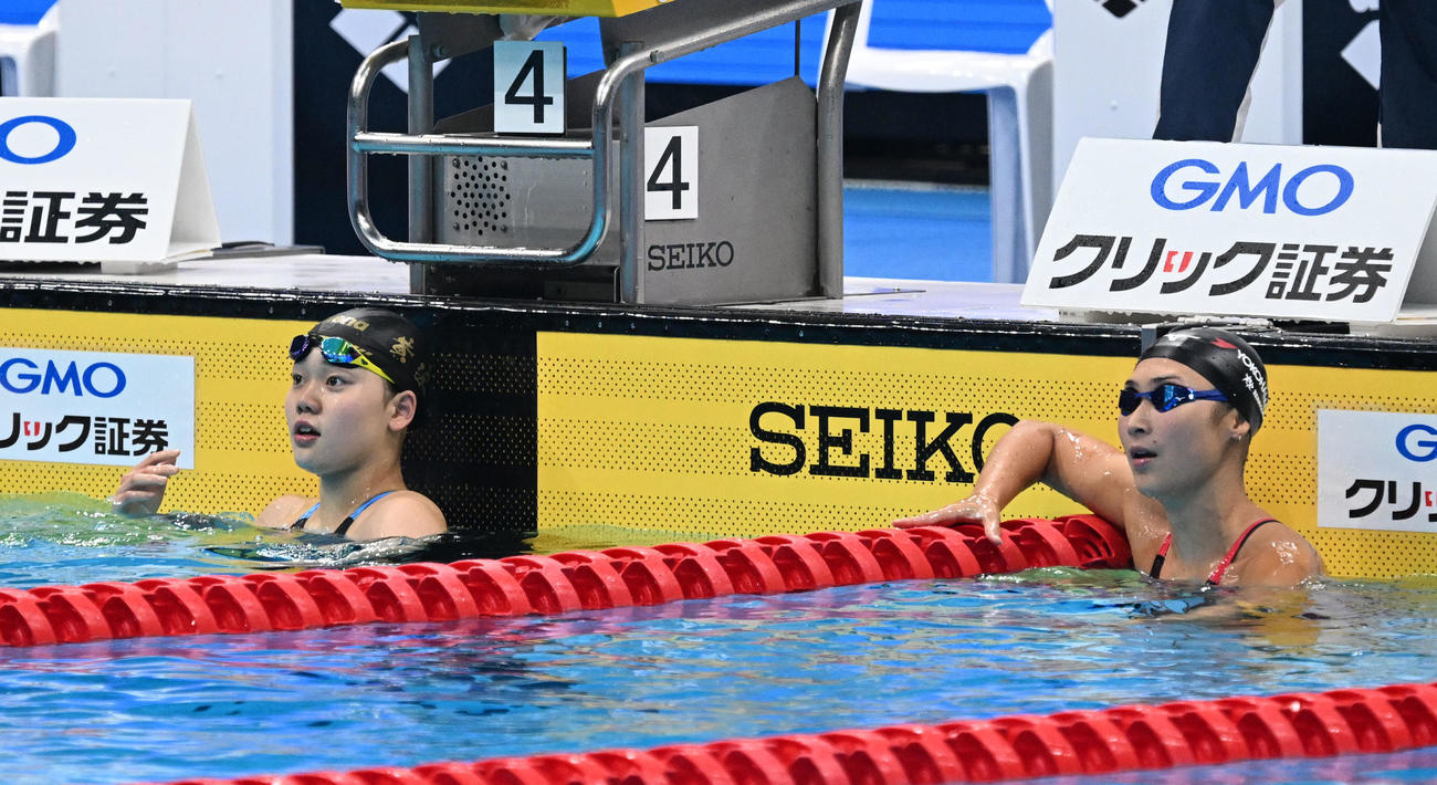 女子100メートルバタフライ決勝　レースを終え、電光掲示板を見る1位の平井（左）と2位の池江（撮影・千葉一成）