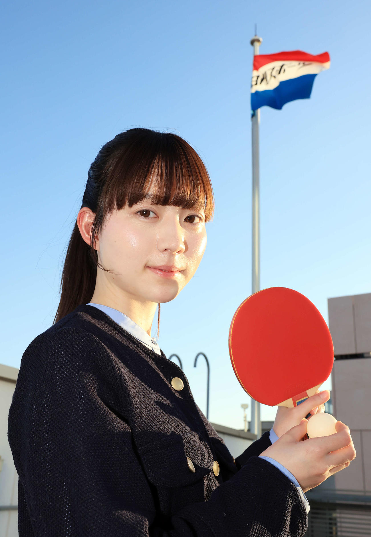 2月、来社した“卓球天使”の菊池日菜は日刊スポーツの社旗を背にほほ笑む