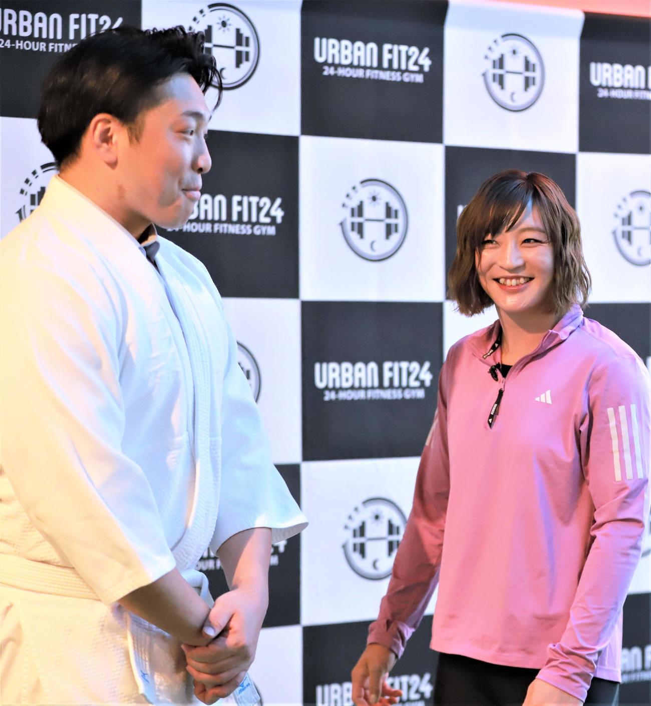 「URBAN FIT24　飯田橋駅前店」のオープニングセレモニーで柔道着を着た男性広報（左）とともに笑顔の柔道女子の角田（撮影・藤塚大輔）