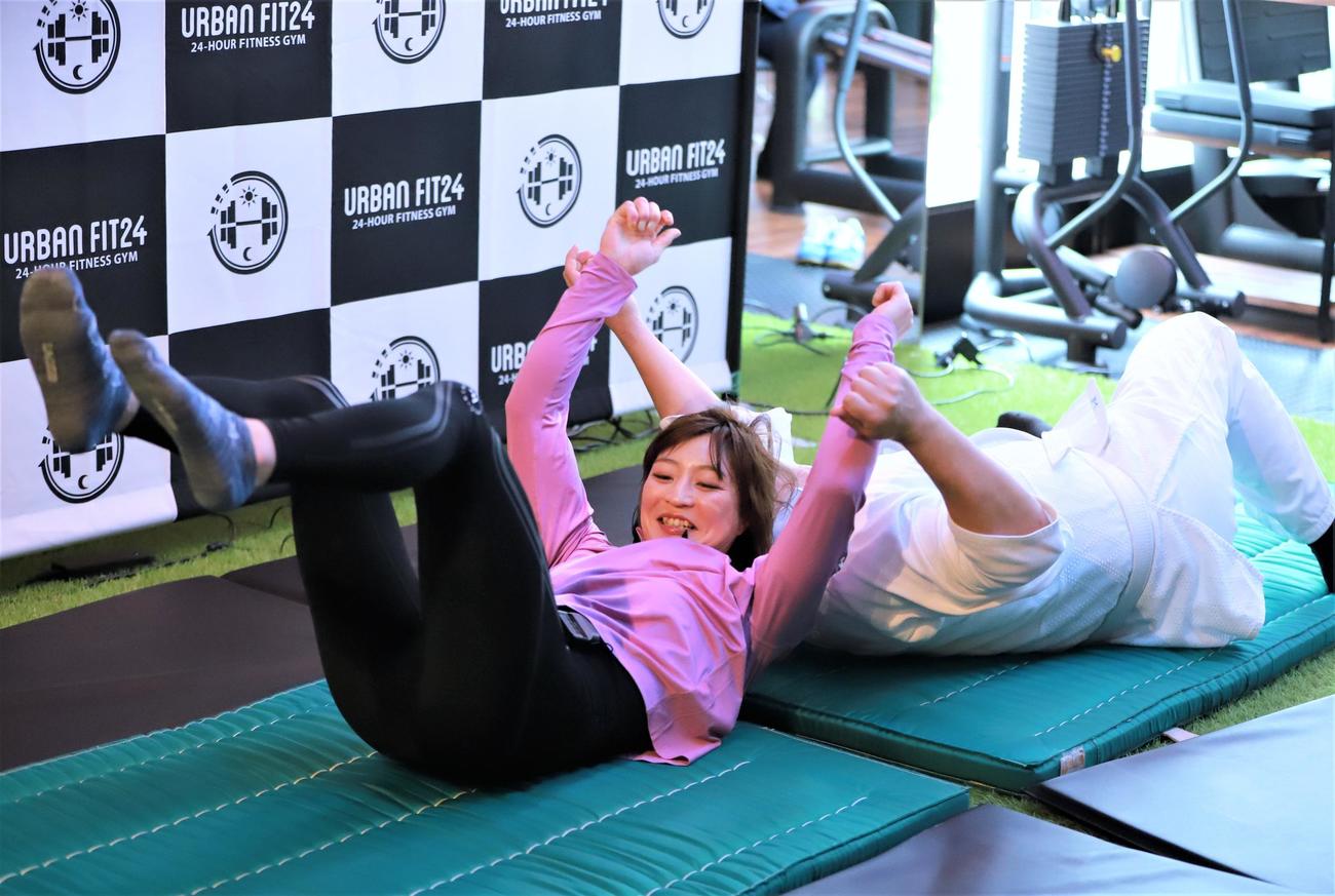 「URBAN FIT24　飯田橋駅前店」のオープニングセレモニーで男性広報にともえ投げを繰り出す柔道女子の角田（手前）（撮影・藤塚大輔）