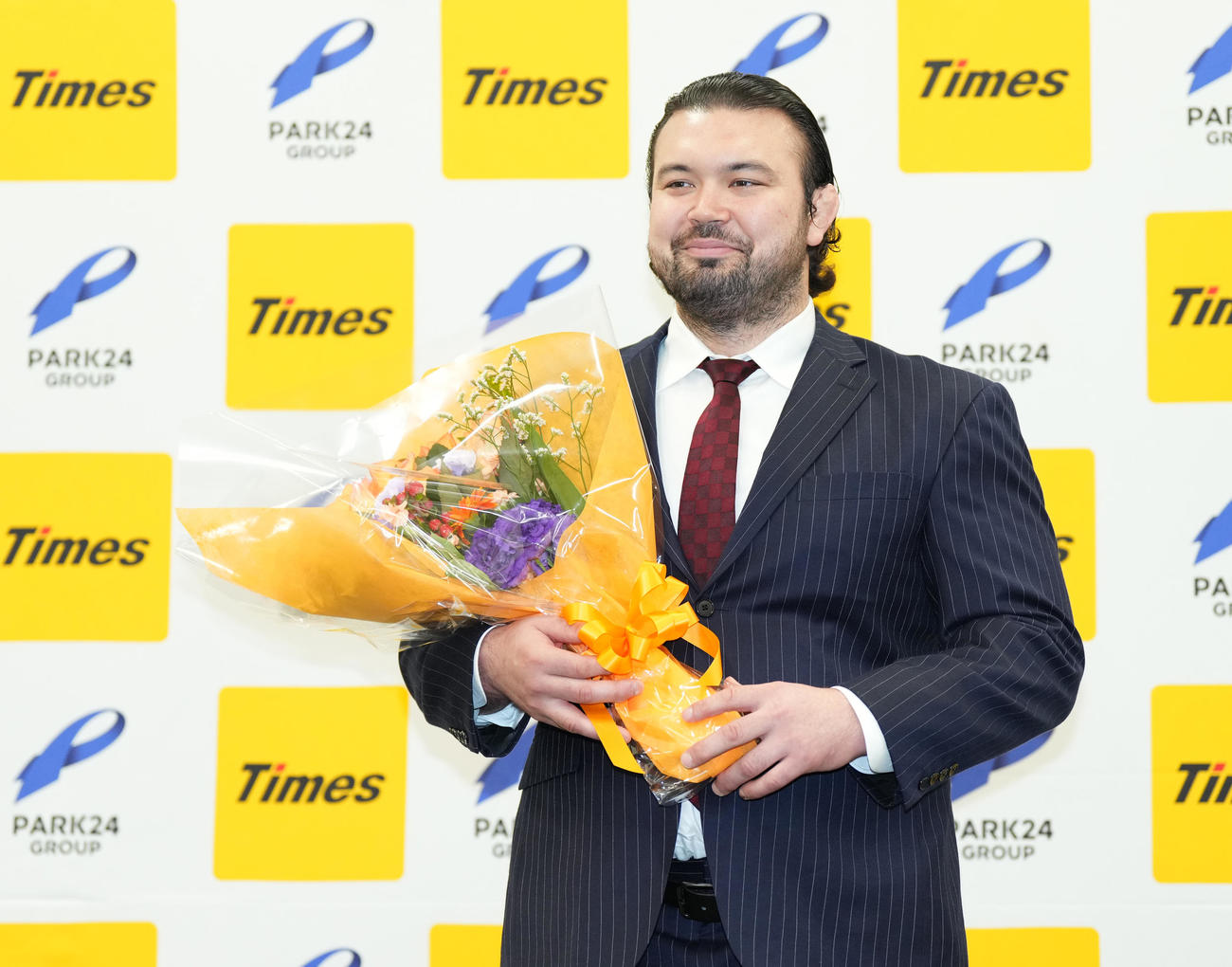 引退会見で受け取った花束を手に笑顔を見せるウルフ・アロン（撮影・菅敏）