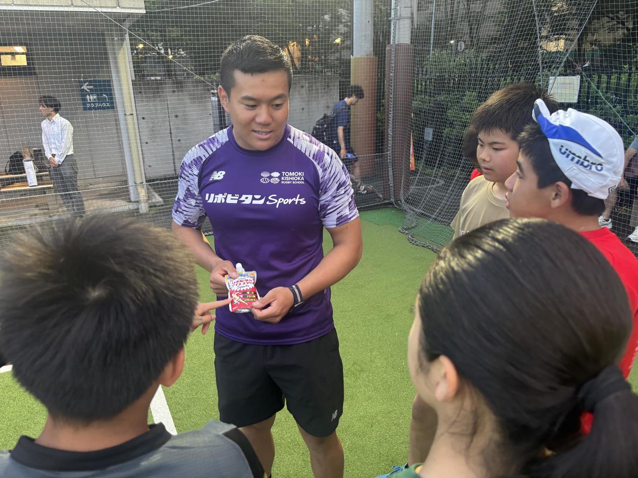 ラグビーアカデミーの子どもたちに大正製薬提供のリポビタンアイススラリーSportsを手渡す岸岡智樹（撮影・松本航）