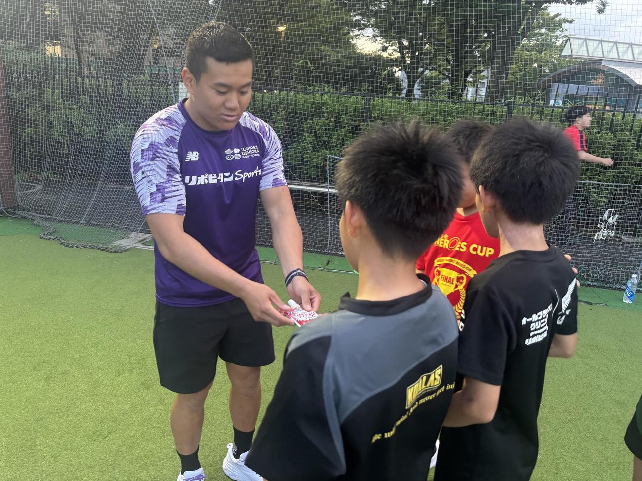 ラグビーアカデミーの子どもたちに大正製薬提供のリポビタンアイススラリーSportsを手渡す岸岡智樹（撮影・松本航）