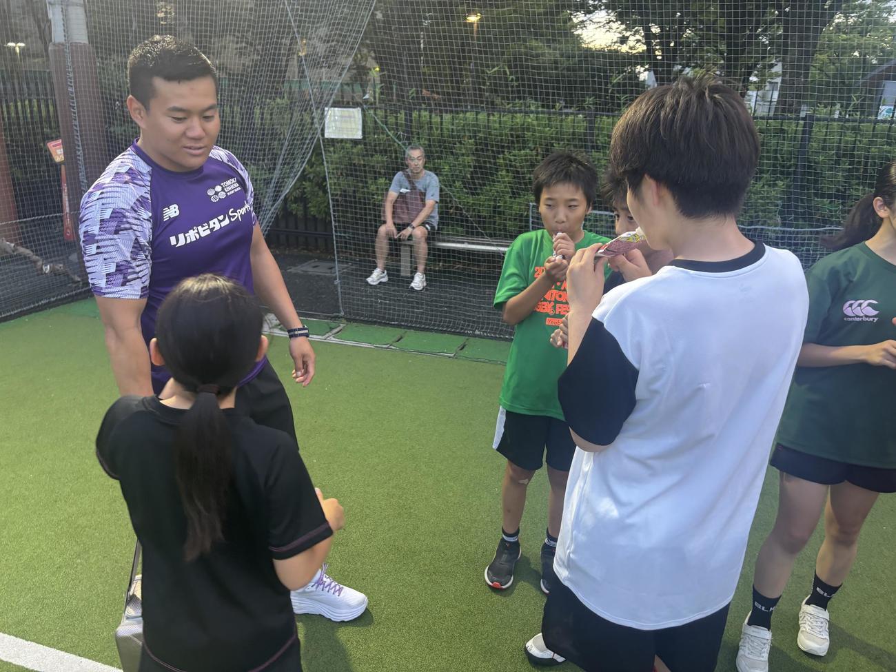 ラグビーアカデミーの子どもたちに大正製薬提供のリポビタンアイススラリーSportsを手渡した岸岡智樹（左）（撮影・松本航）