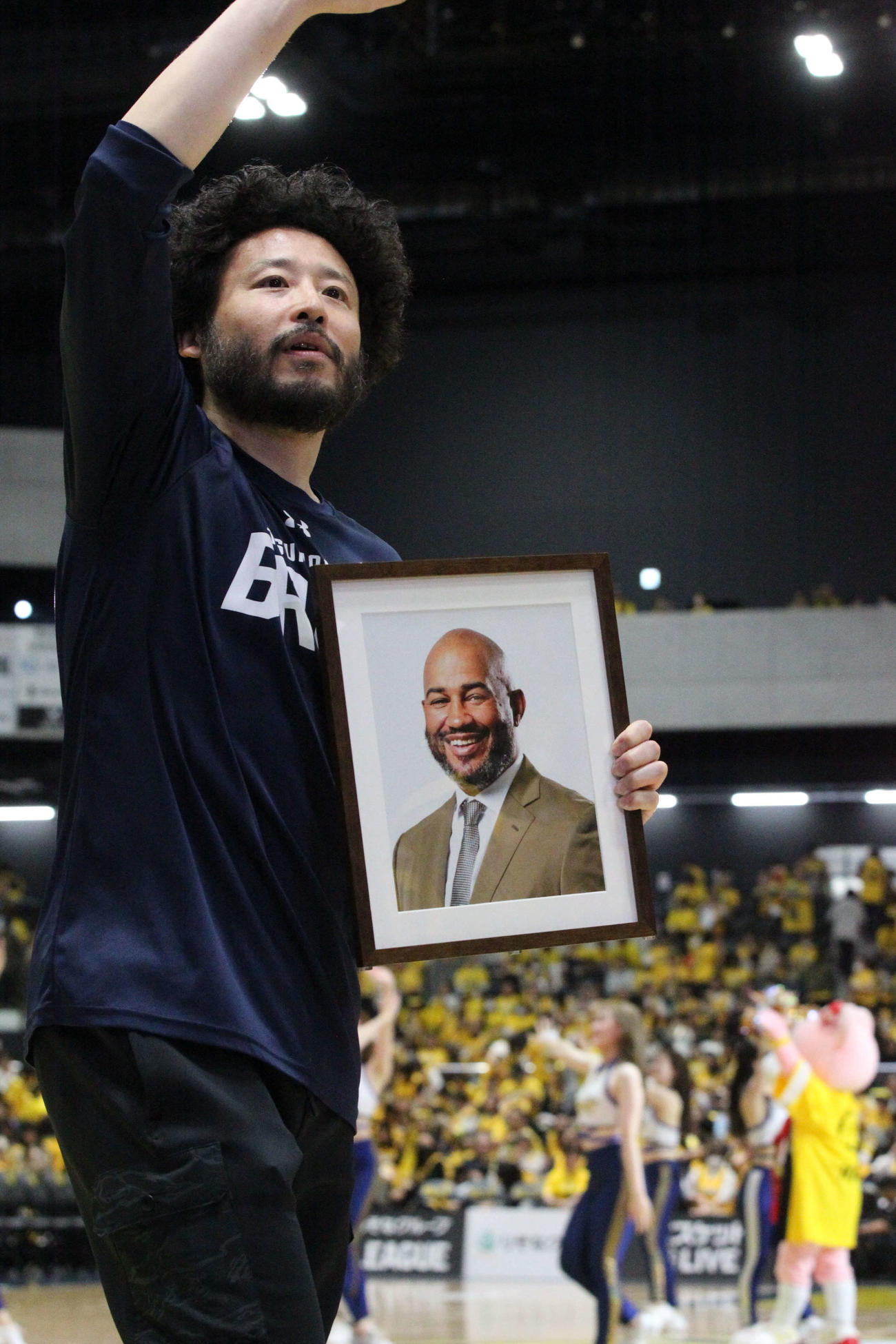 宇都宮対千葉J　2月に急死したケビン・ブラスウェルHCの遺影を持ってファンに勝利を報告する宇都宮の田臥勇太＝25年５月19日