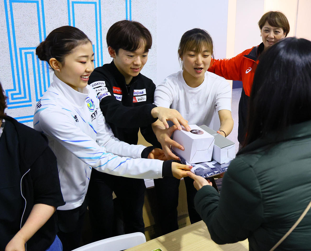 フィギュアの五輪対策合宿公開練習で、グッズ販売の手伝いをする左から千葉百音、鍵山優真、坂本花織（撮影・藤尾明華）