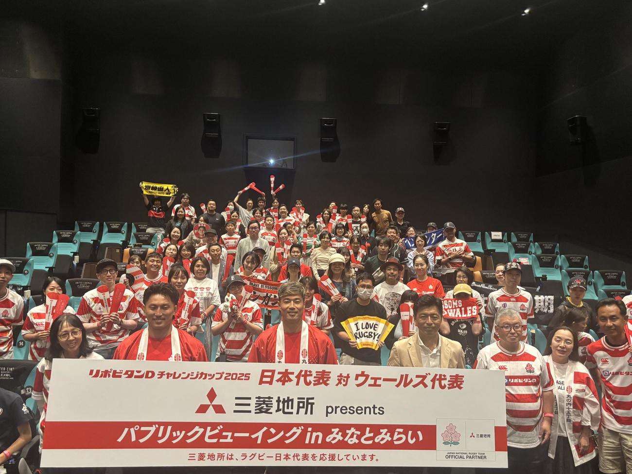 ラグビー日本代表戦のPVで盛り上がった参加者と、パネルを持つ左から古川聖人、山田章仁、豊原謙二郎氏（撮影・松本航）