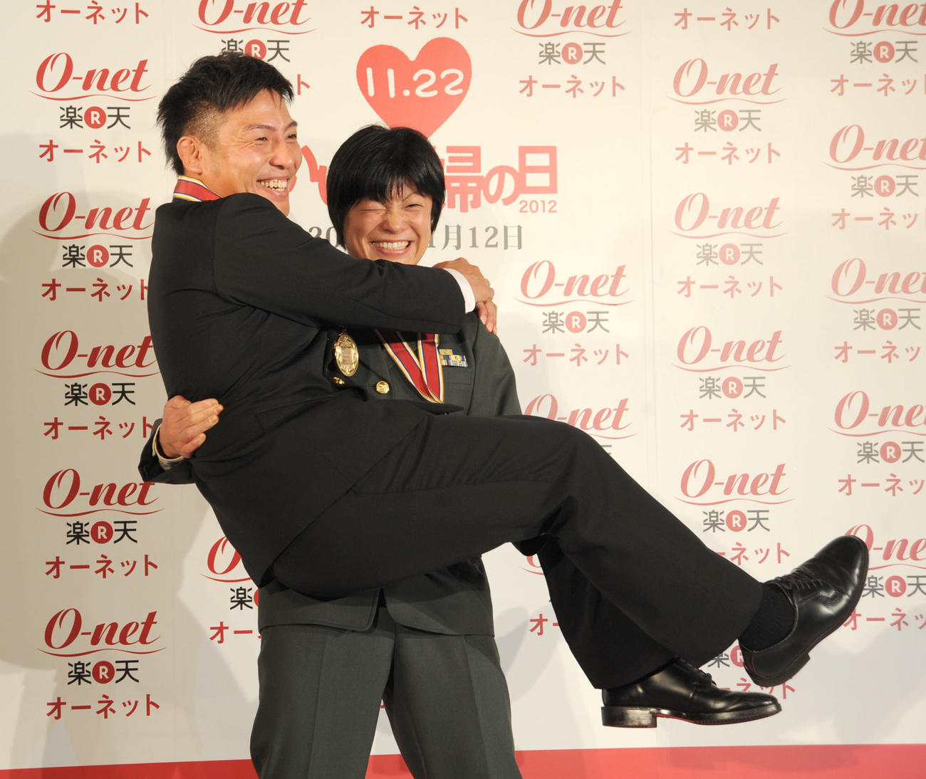 「いい夫婦の日パートナー・オブ・ザ・イヤー　2012」に選ばれ、お姫さまならぬお殿さま抱っこをするレスリングの小原日登美さん（右）と夫の康司さん