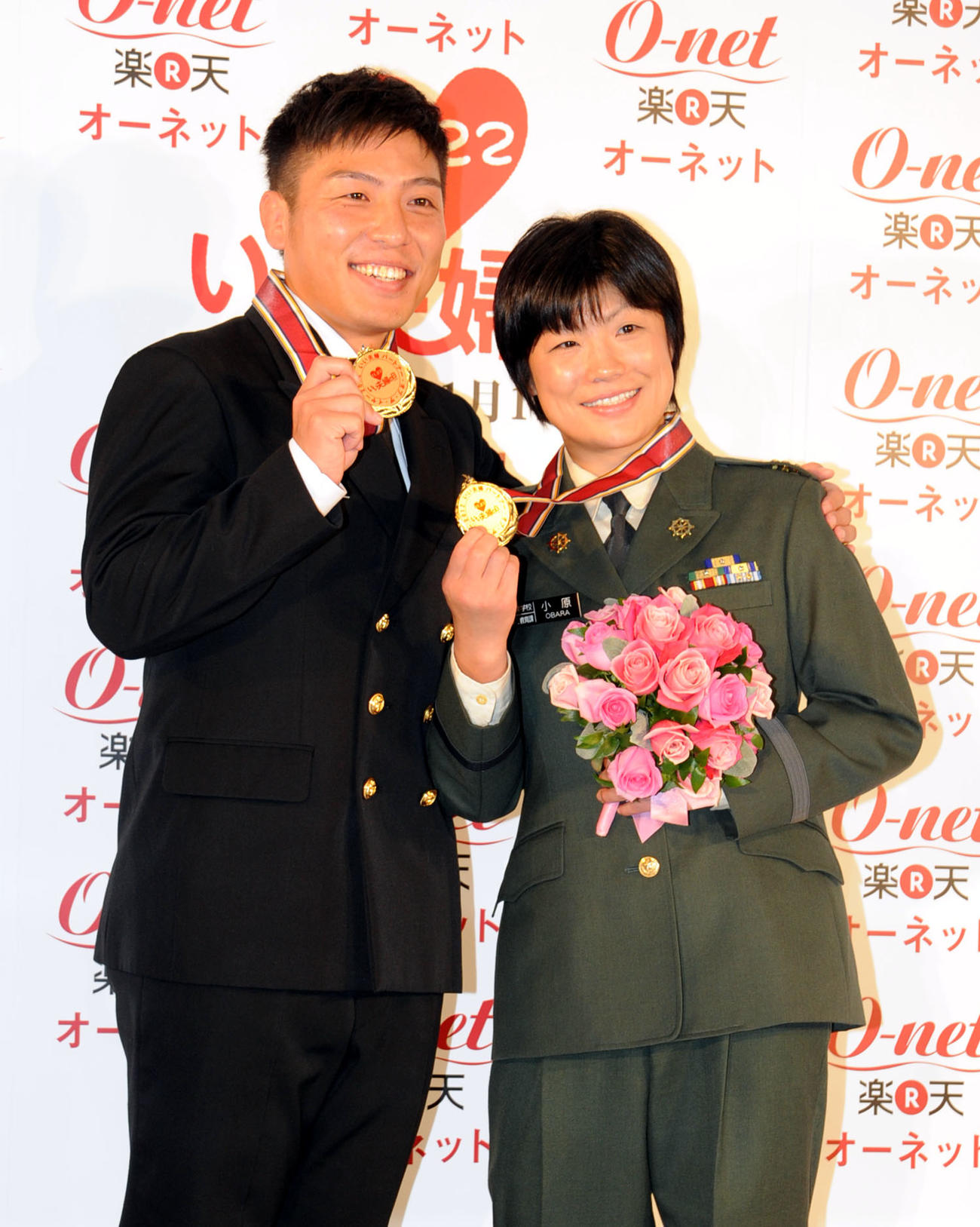 「いい夫婦の日パートナー・オブ・ザ・イヤー　2012」に選ばれ、特別につくられた金色のメダルを2人で掲げるレスリングの小原日登美さん（右）、康司さん夫妻