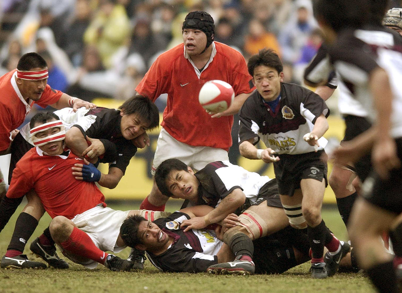 02年２月３日のラグビー日本選手権決勝　サントリー対神戸製鋼　　後半23分、永友洋司（右）は絶妙のパスを出す。左から神戸製鋼FW弘津英司、TB元木由記雄、サントリーTB山口大輔、CTBイエレミア、FW大久保直弥、神戸製鋼FW中道紀和（上）