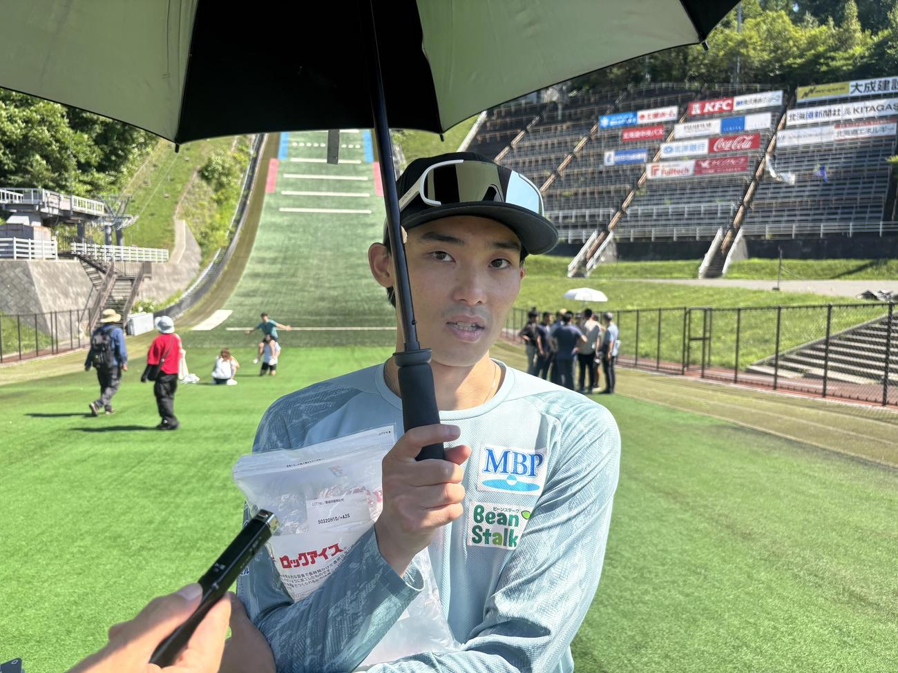 今季初優勝した小林朔は氷を抱えながら、傘をさして取材に対応する（撮影・保坂果那）