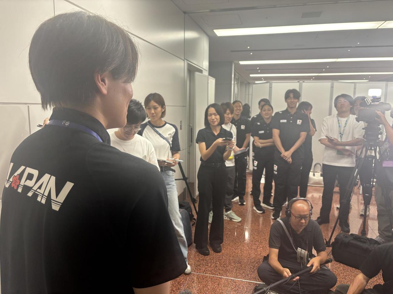 水泳の世界選手権から帰国した松下知之（左）に質問する村佐達也（中央右）（撮影・松本航）