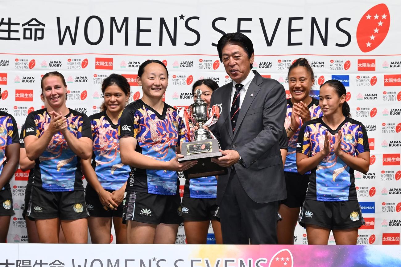 太陽生命ウィメンズセブンズシリーズで年間総合優勝を飾り、日本協会の土田雅人会長（右）からトロフィーを受け取るながとの平野優芽（C）JRFU