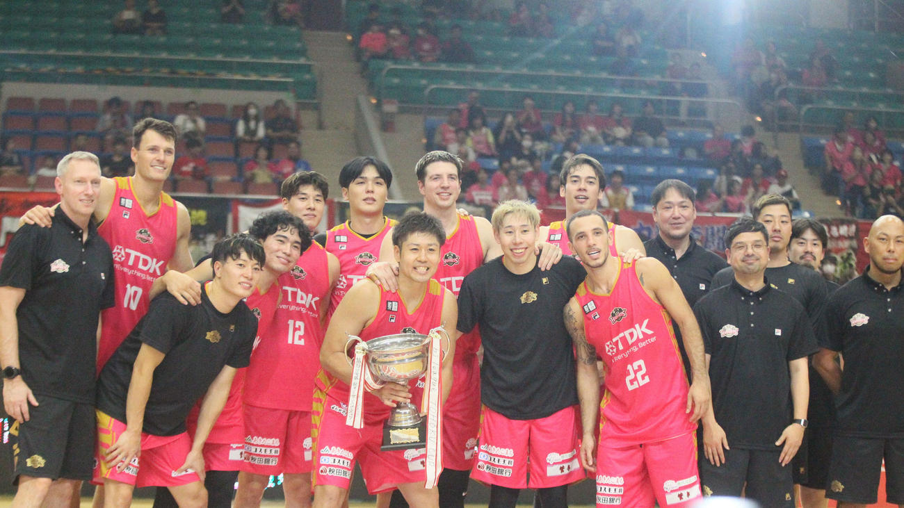 優勝カップとともに記念写真に納まるB1秋田の選手、コーチ陣たち（撮影・高橋香奈）