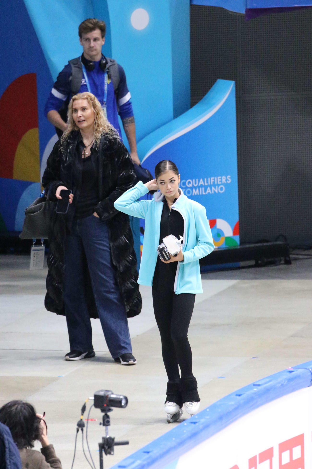 ミラノ・コルティナ冬季五輪最終予選の公式練習前、エテリ・トゥトベリゼ・コーチ（右から2人目）と待つアデリア・ペトロシャン（右）（撮影・松本航）