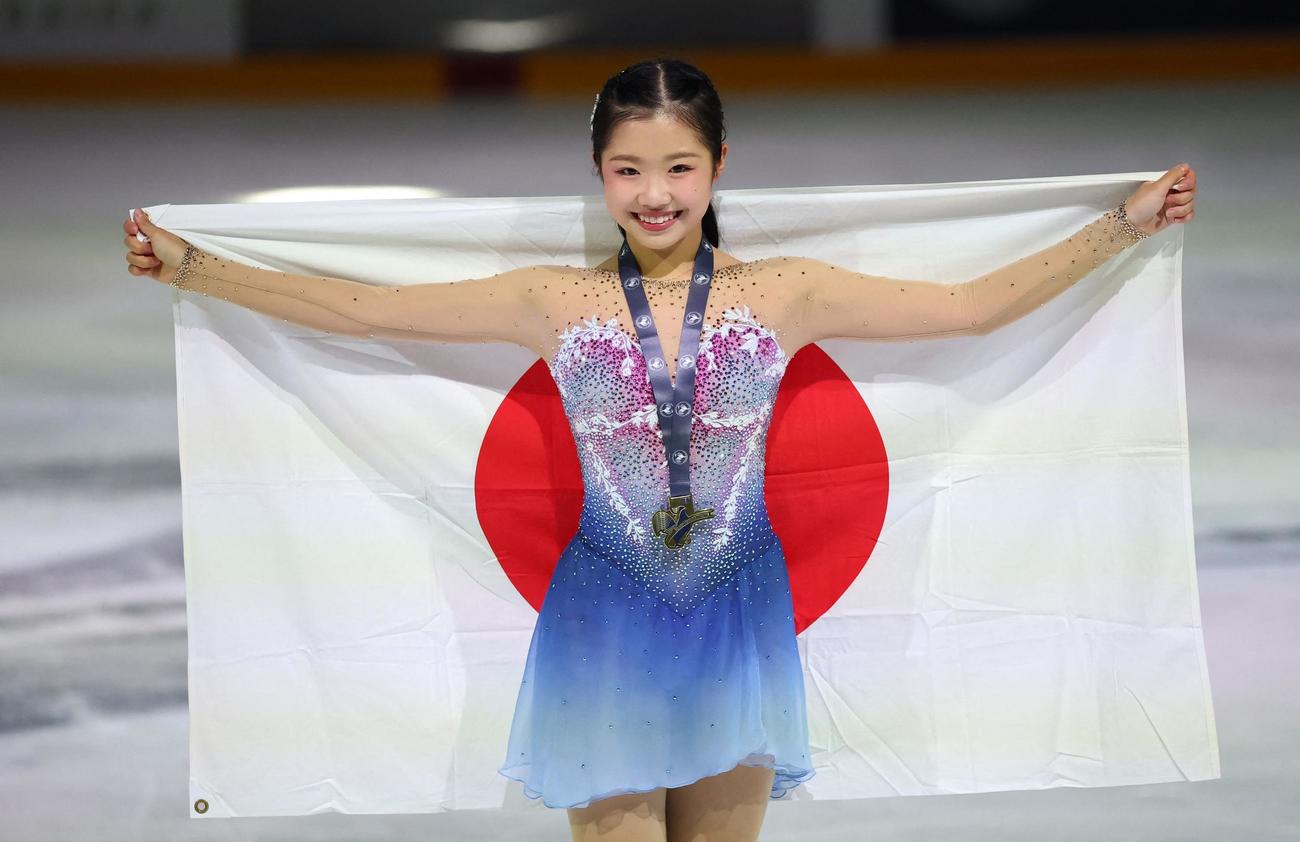 GPシリーズ第1戦フランス大会で優勝し、日の丸を背に笑顔でポーズを決める中井亜美（ロイター）