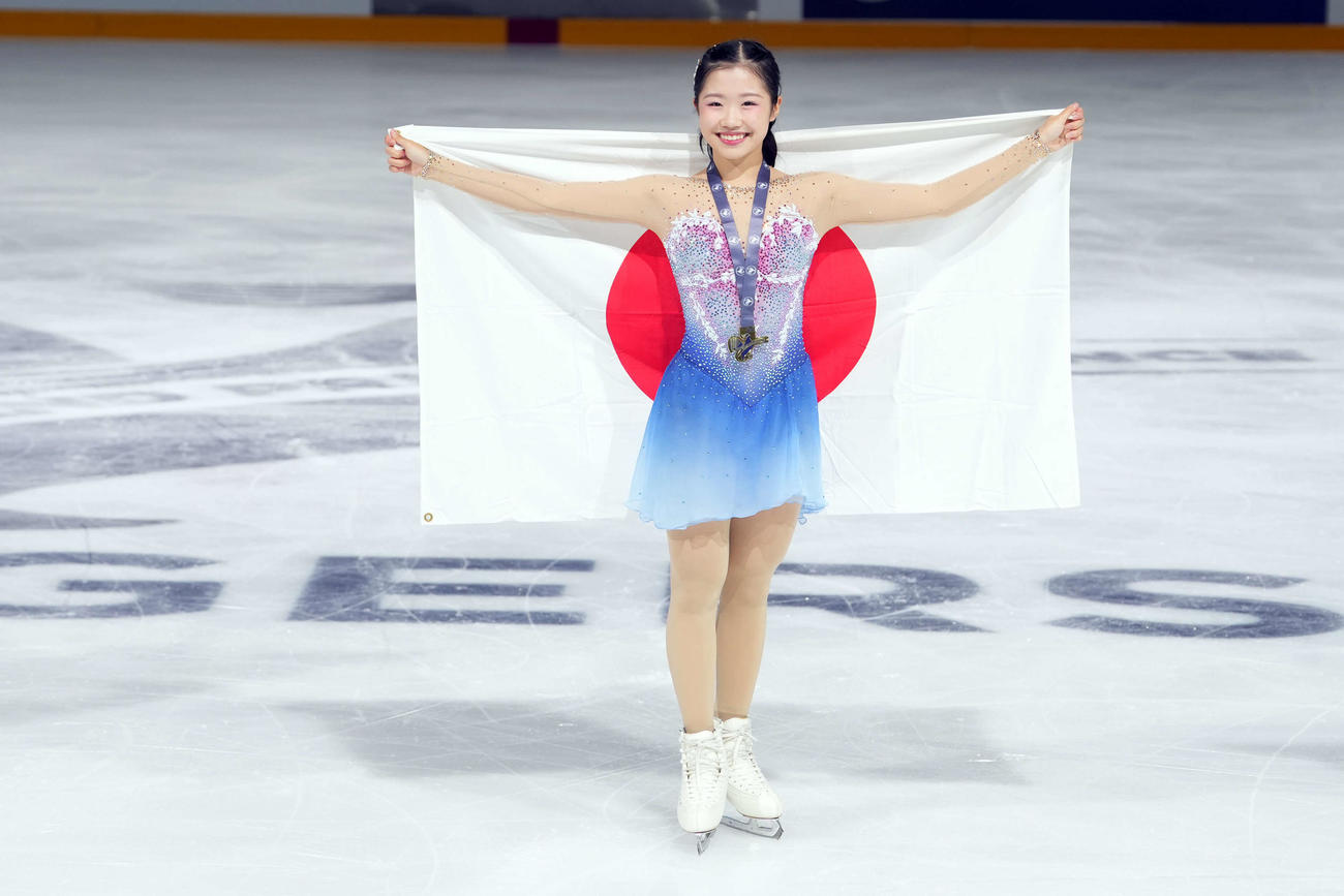 グランプリシリーズ初出場優勝を果たした中井は日の丸を掲げ、笑顔を見せる（撮影・パオロ　ヌッチ）