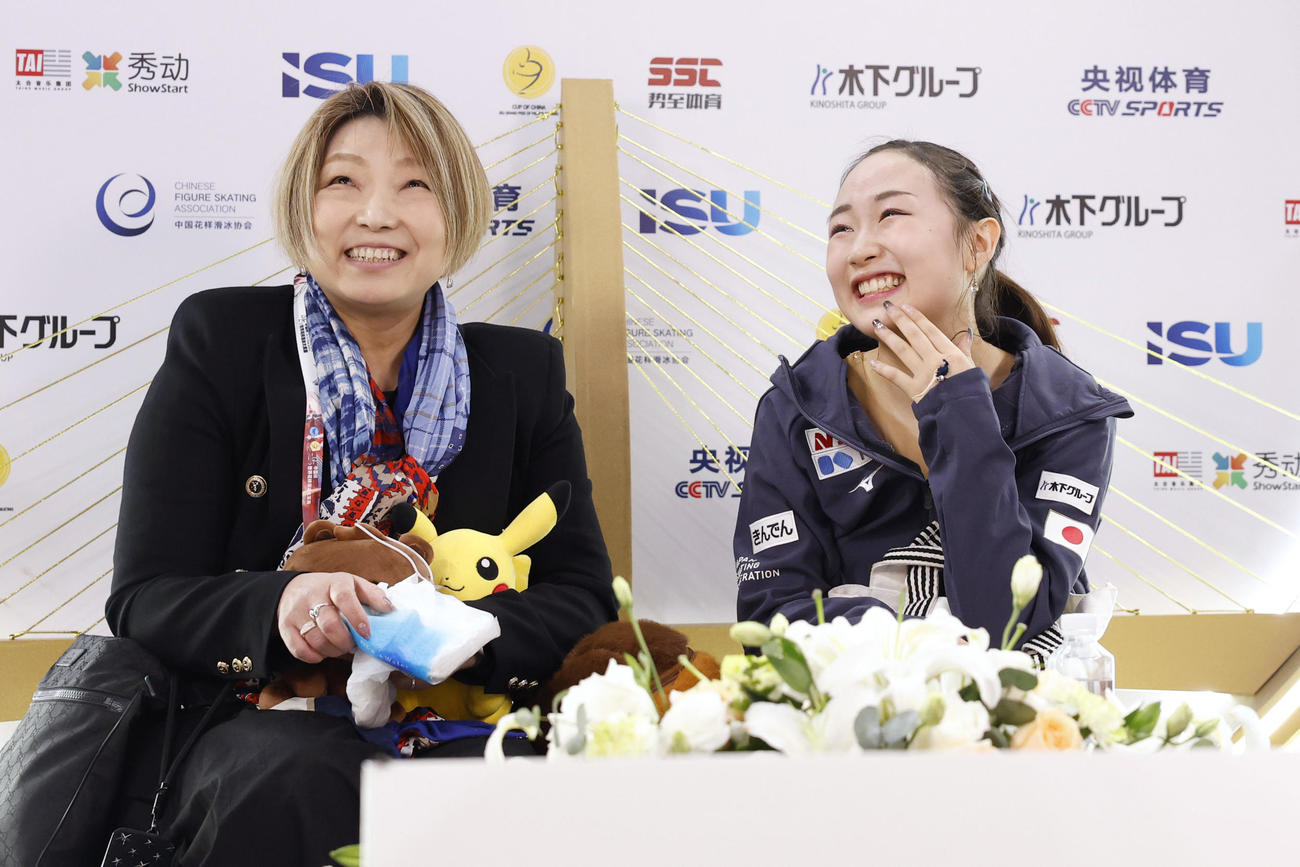 女子SPの得点を確認し、笑顔の松生理乃。左は本郷裕子コーチ＝重慶（共同）