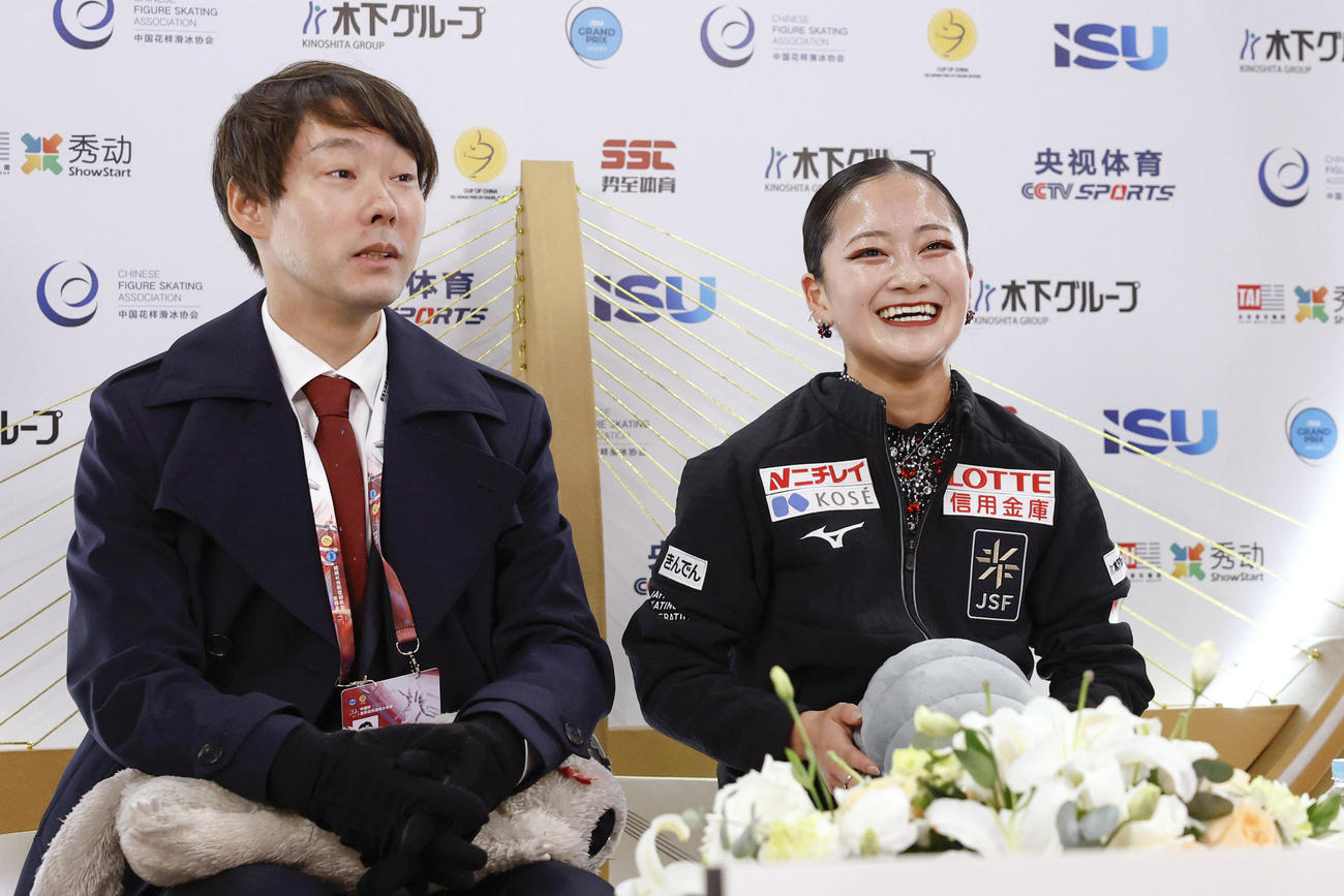 女子SPの得点を確認し、笑顔の渡辺倫果。左は中庭健介コーチ＝重慶（共同）