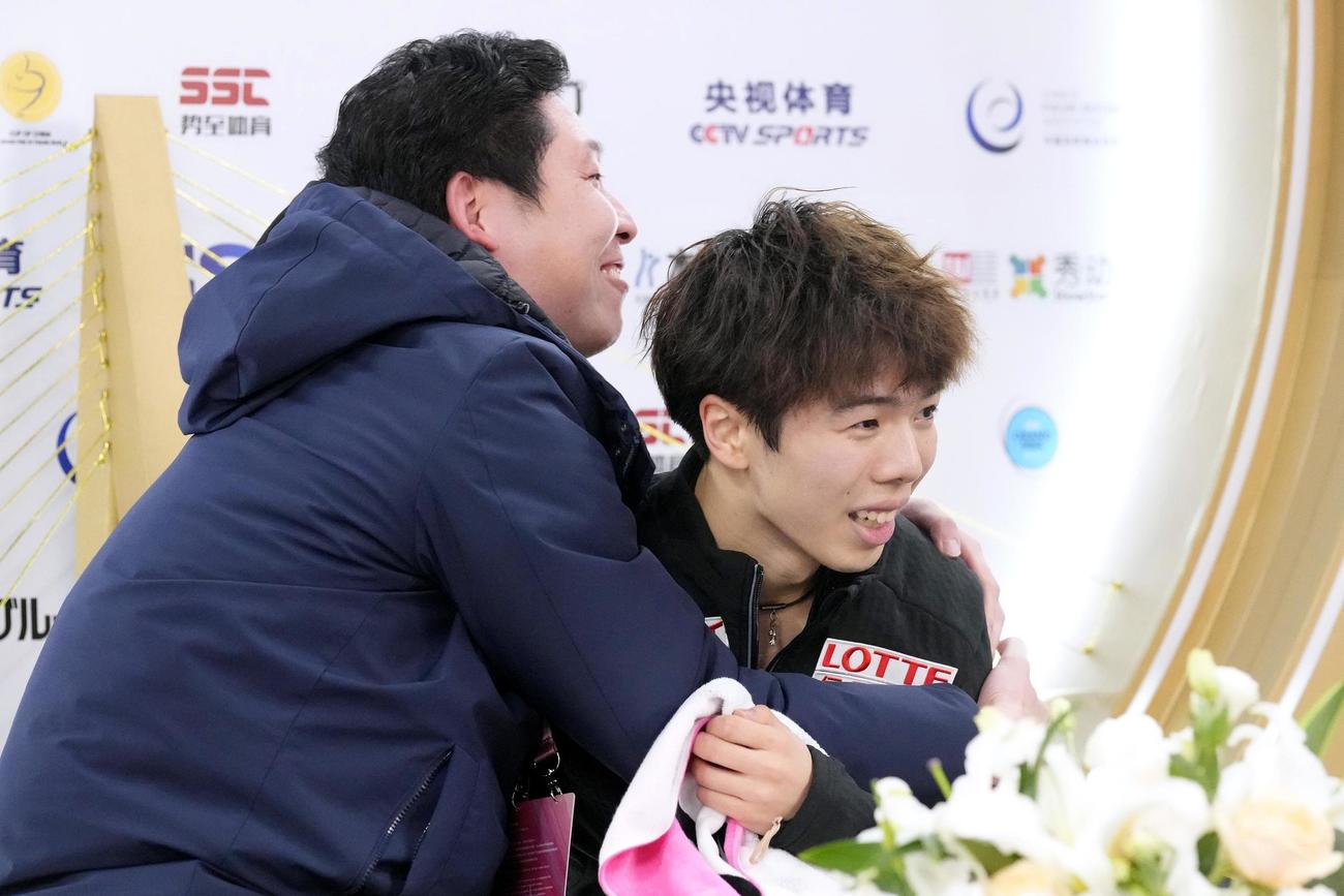 男子フリーの得点を確認し、日下匡力コーチ（左）と抱き合う佐藤駿（共同）