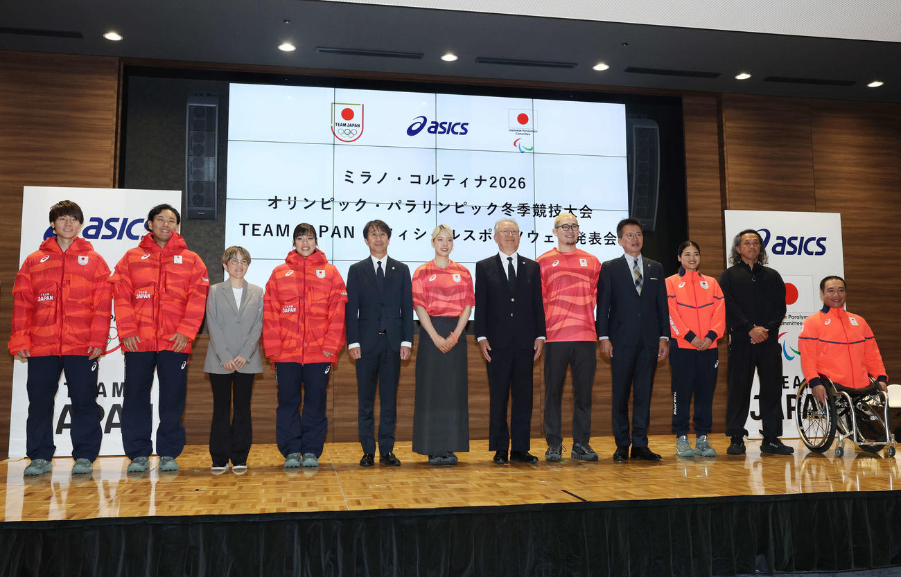 日本代表オフィシャルスポーツウエアを着て写真に納まるミラノ・コルティナ五輪、パラリンピックの選手たち、左から森重、森、アシックス甲田知子常務執行役員、浮田、原田雅彦副団長、江村、伊東秀仁団長、宮食、日本代表選手団荒井秀樹副団長、細山田、大堀亮アパレル・エクィップメント統括部開発部マネジャー、鈴木（撮影・宮地輝）