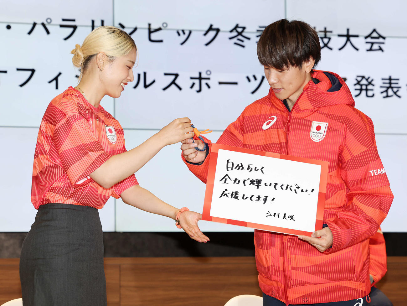 「ミラノ・コルティナ2026五輪・パラリンピック冬季競技大会TEAM JAPANオフィシャルスポーツウエア発表記者会見」で江村（左）からのメッセージとチャームを受け取る森重（撮影・宮地輝）