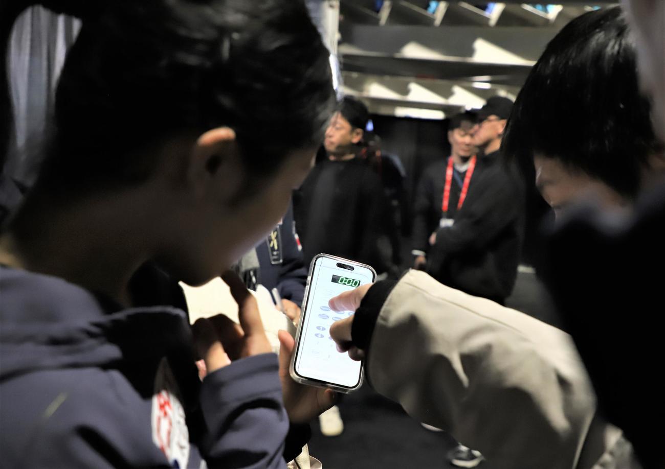 GPシリーズ第3戦スケートカナダ　公式練習後にスマートフォンを取り出して電子レンジの使い方について報道陣に相談する中井（撮影・藤塚大輔）