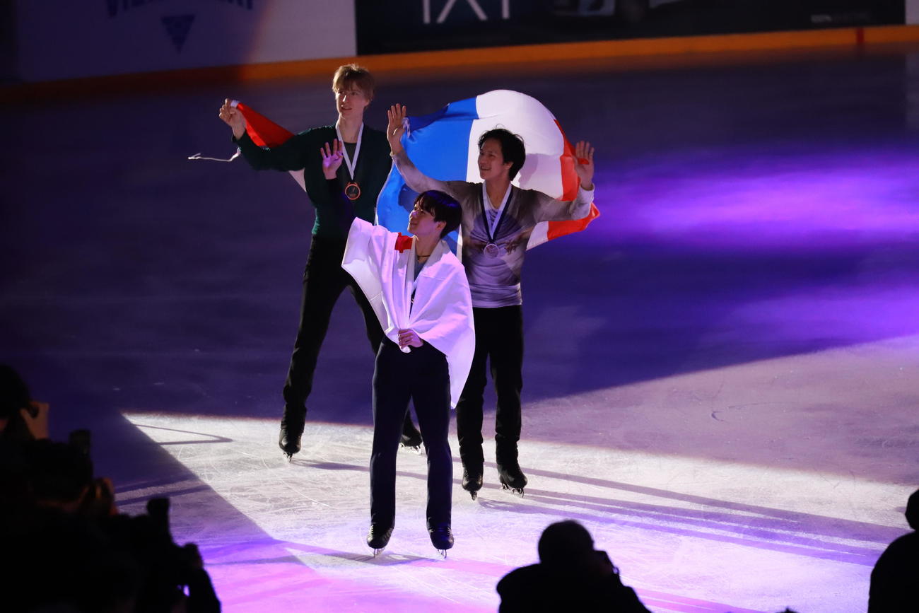 GPフィンランド大会男子表彰式　優勝した鍵山優真（中央）は2位のアダム・シャオイムファ（右）、3位のスティーブン・ゴゴレフと場内を1周する（撮影・松本航）