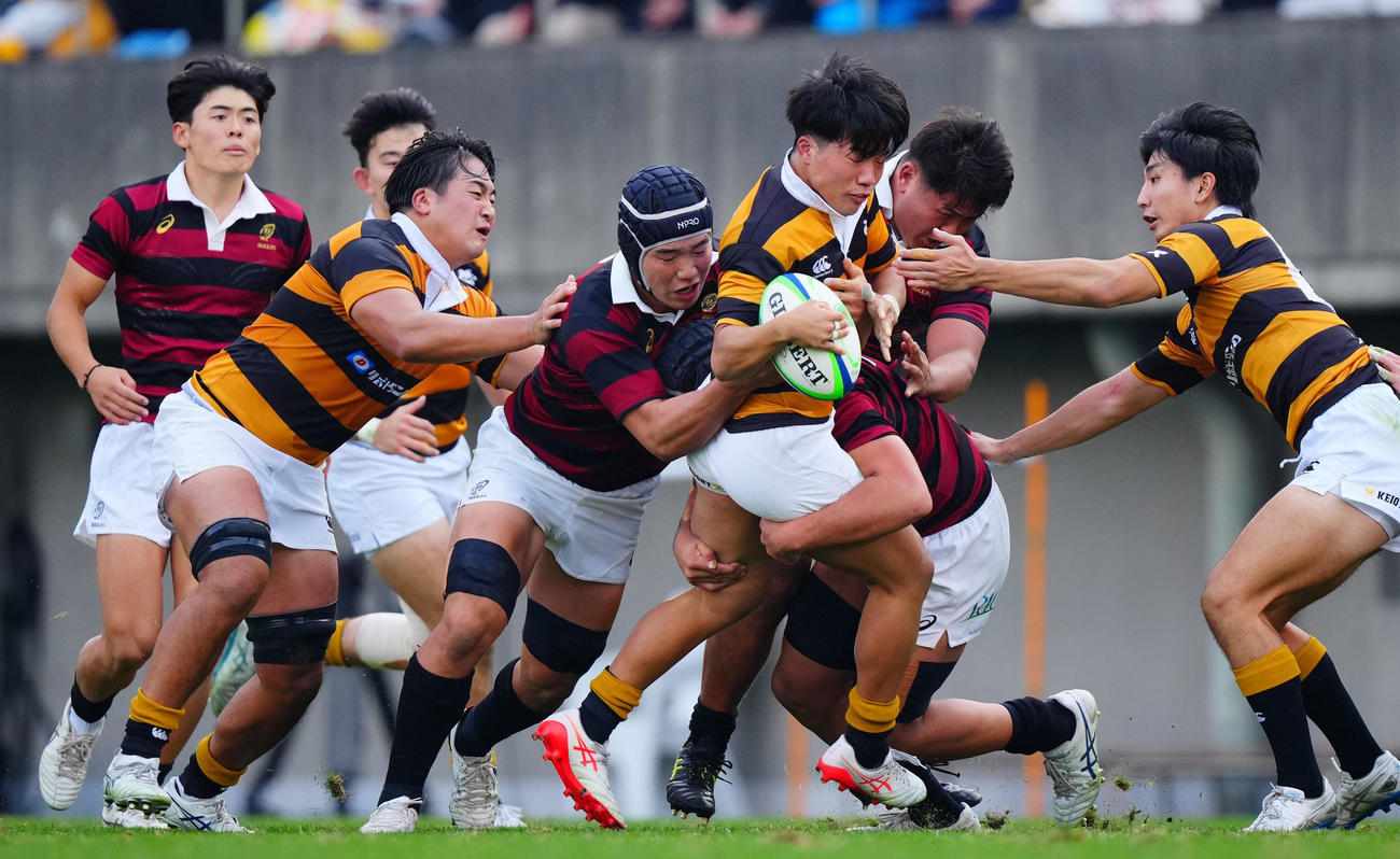 早大対慶大　前半、激しいタックルで慶大SO小林（中央）の突破を阻む早大の選手たち（撮影・垰建太）