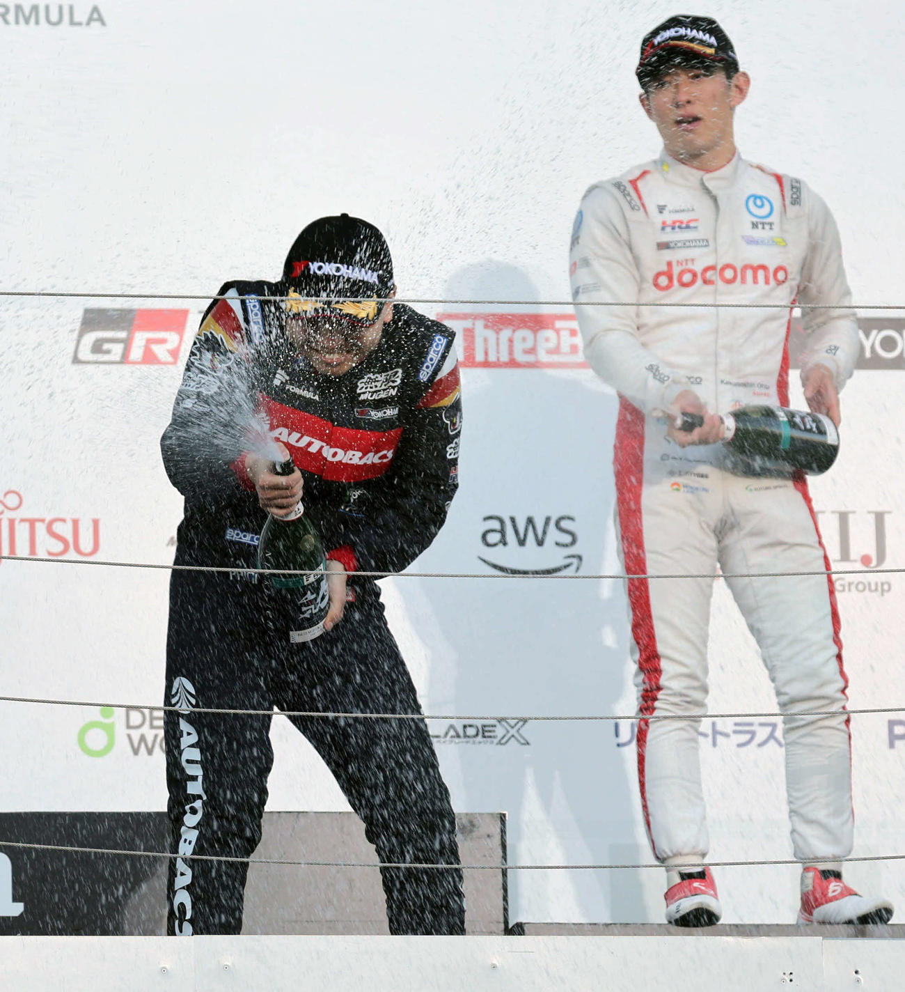 スーパーフォーミュラ最終戦、スパークリング日本酒を浴びる岩佐歩夢。右は太田格之進（撮影・宮崎幸一）