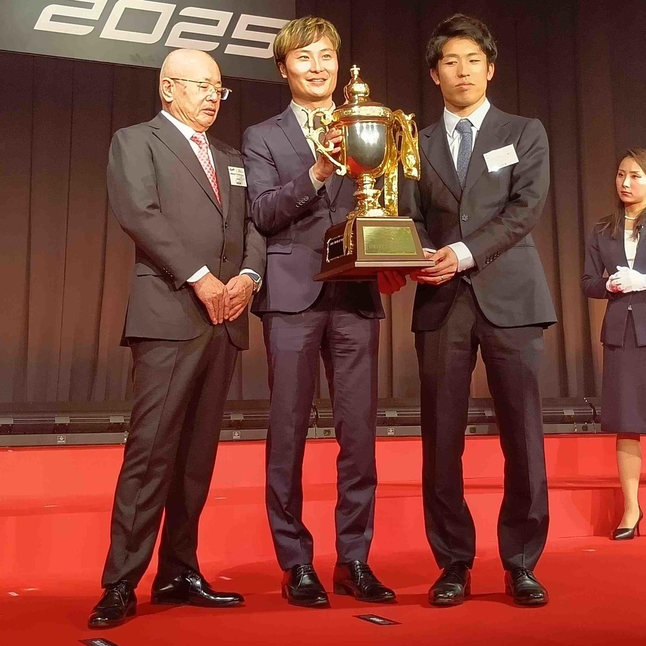 スーパーGTのGT500クラス年間王者トロフィーを手にする坪井翔と山下健太、坂東正明代表（右から）