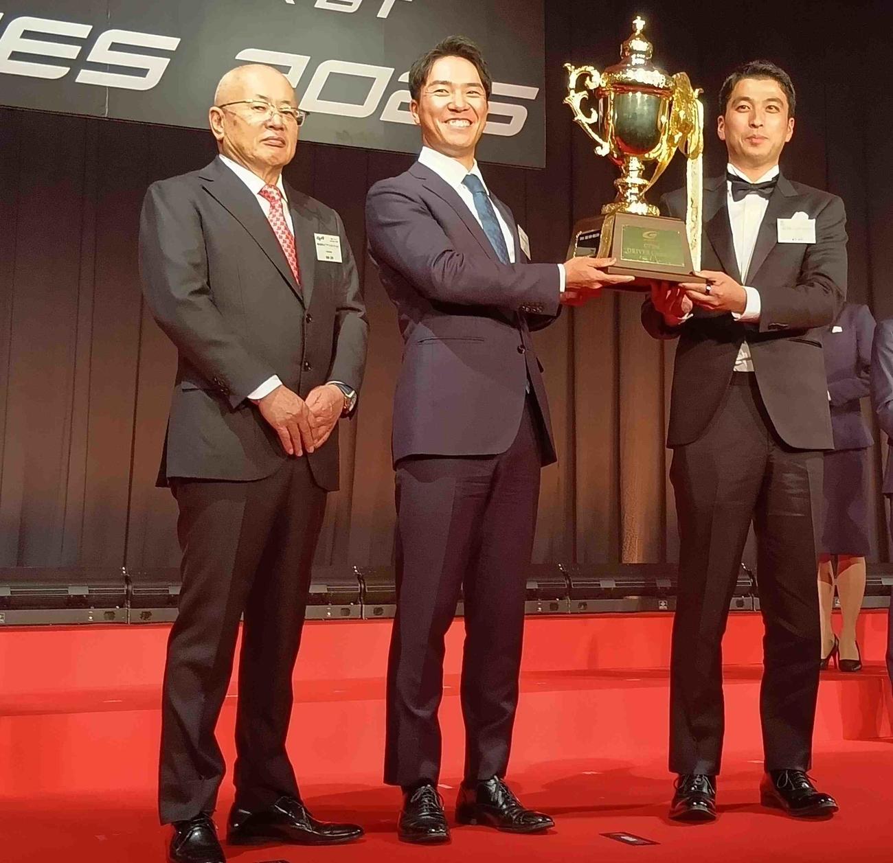 スーパーGTのGT300クラス年間王者トロフィーを手にする蒲生尚弥と菅波冬悟、坂東正明代表（右から）