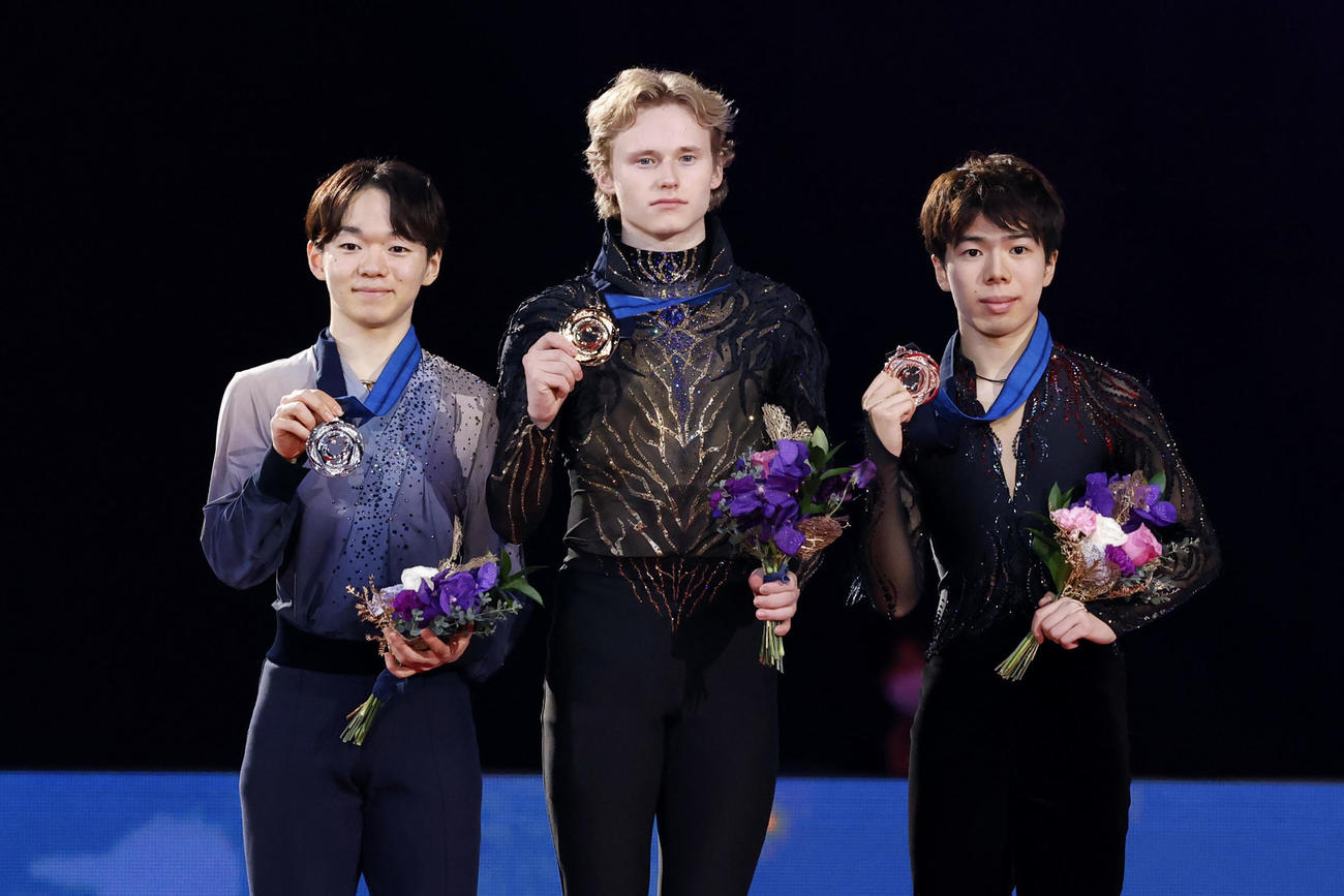 男子の表彰式でメダルを掲げる（左から）2位の鍵山優真、優勝のイリア・マリニン、3位の佐藤駿＝IGアリーナ