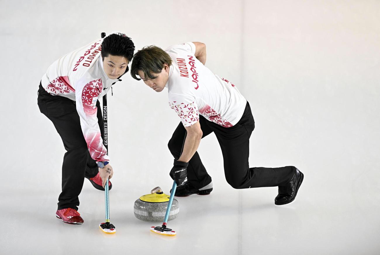 男子プレーオフ　中国戦の第6エンド、スイープする小泉（右）と山本＝ケロウナ（共同）