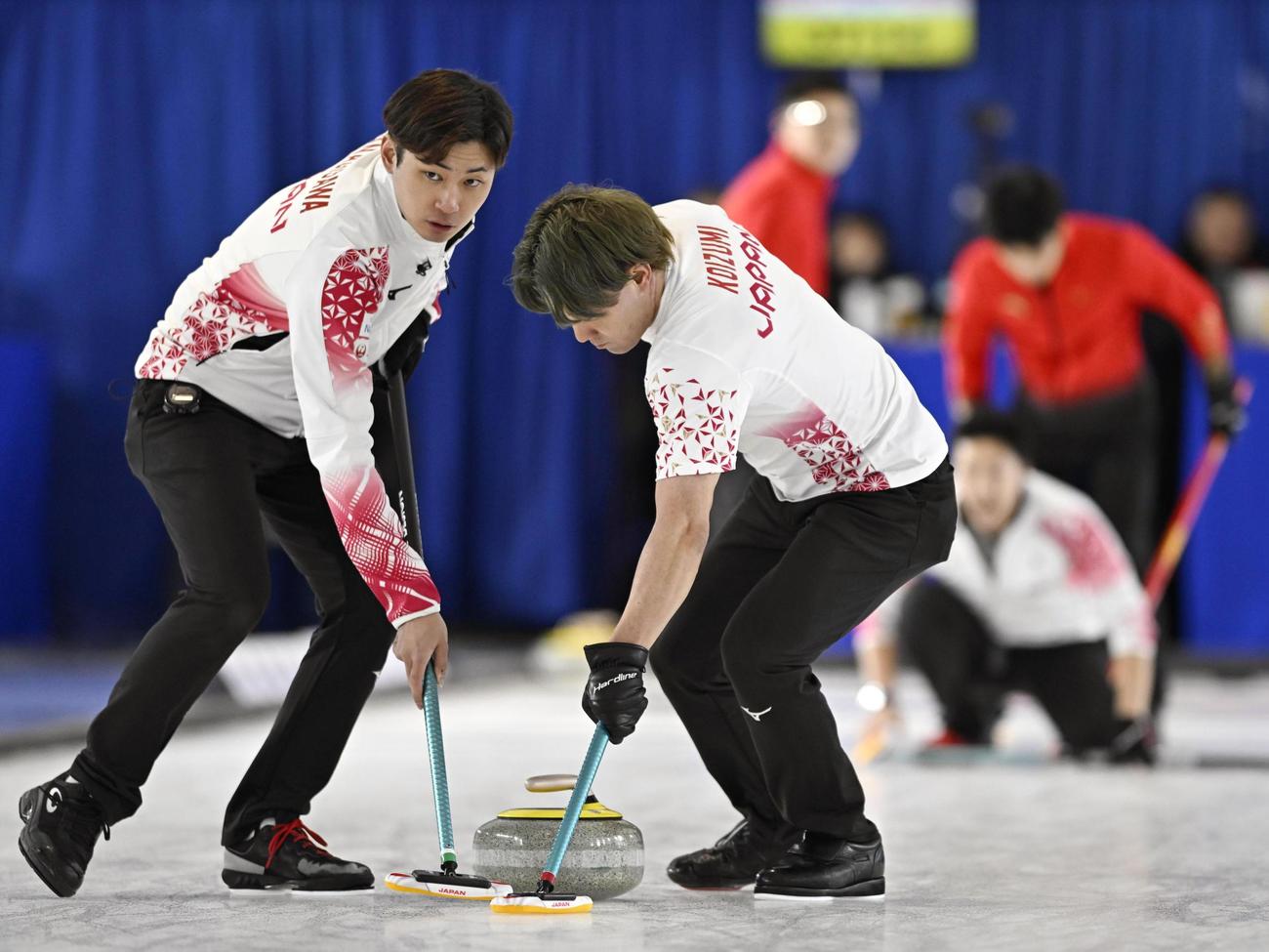 男子プレーオフ　中国戦の第1エンド、スイープする柳沢（左）と小泉＝ケロウナ（共同）
