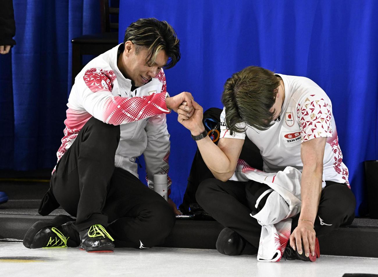 男子プレーオフで敗れて五輪出場を逃し、座り込んで悔しがる山口（左）と小泉＝ケロウナ（共同）