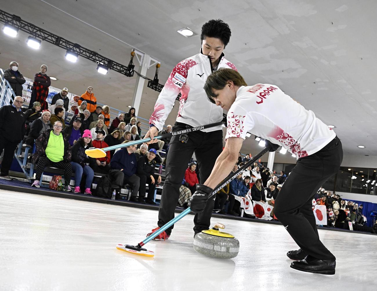 男子プレーオフ　中国戦の第7エンド、スイープする小泉。左は山本＝ケロウナ（共同）