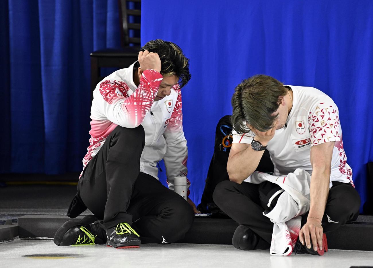 男子プレーオフで敗れて五輪出場を逃し、座り込んで悔しがる山口（左）と小泉＝ケロウナ（共同）