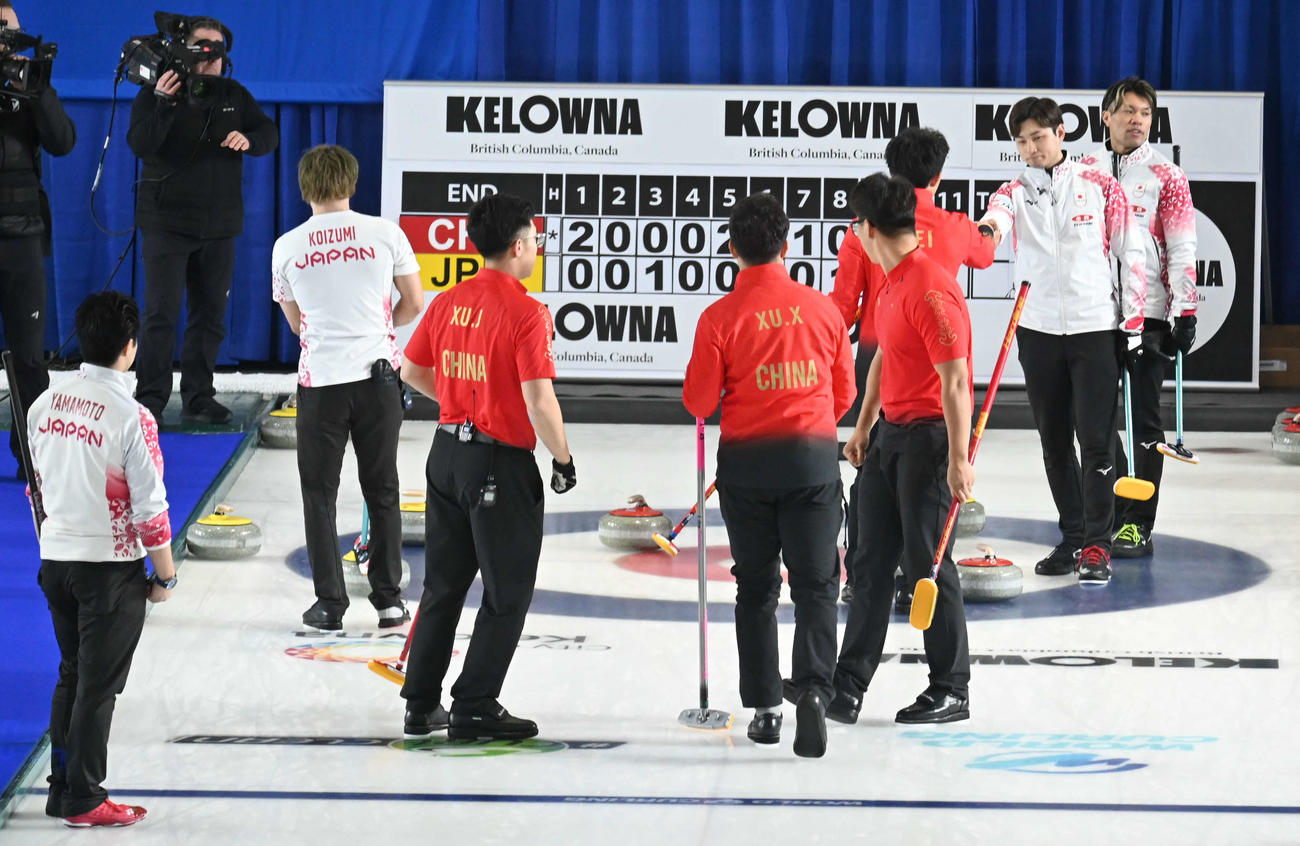 第9エンド、負けを認めて握手を求める柳沢（右から2人目）ら男子日本代表（撮影・飯岡大暉）