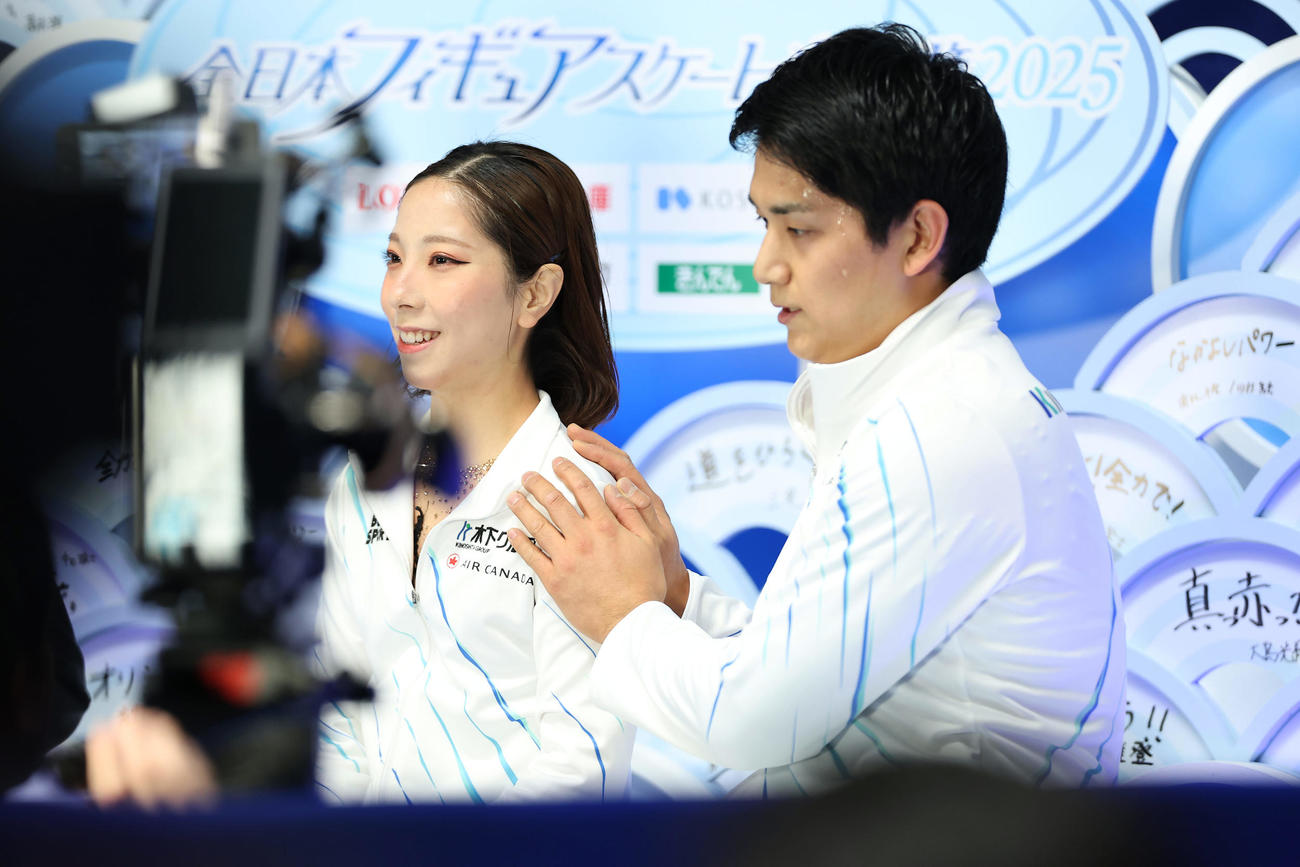 ペアSPの演技を終え、キス・アンド・クライ木原（右）に肩をさわられ笑顔を見せる三浦（撮影・前田充）