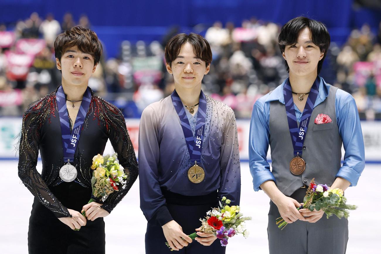 フィギュアスケートの全日本選手権で、2年連続2度目の優勝を果たしミラノ・コルティナ冬季五輪代表に決まった鍵山優真。左は2位の佐藤駿、右は3位の三浦佳生＝20日、東京・国立代々木競技場（共同）